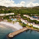 Aerial view of Mexican resorts for destination weddings, featuring pools and lush green hills.