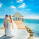 A bride and groom standing on a dock by the ocean, surrounded by romance and tranquility.