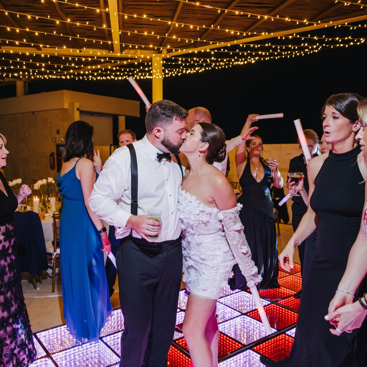 A couple shares a kiss on a glowing dance floor during their destination wedding celebration.