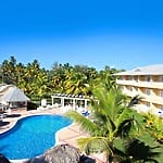 Budget-friendly all-inclusive resort with pool, palm trees, yellow building—ideal for destination weddings.