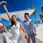 Bride holding bouquet, smiling with groom and friends at a stunning Jamaica destination wedding.