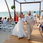 The bride and groom walk barefoot down the aisle, embracing the joy of their destination wedding while using a destination wedding calculator to plan their celebration.