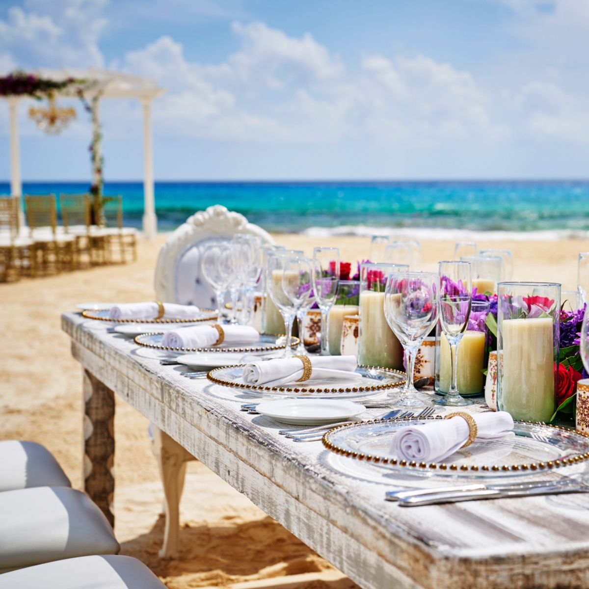 An elegant table arrangement for a destination wedding in Cancun, beautifully adorned with glassware, candles, and fresh flowers.