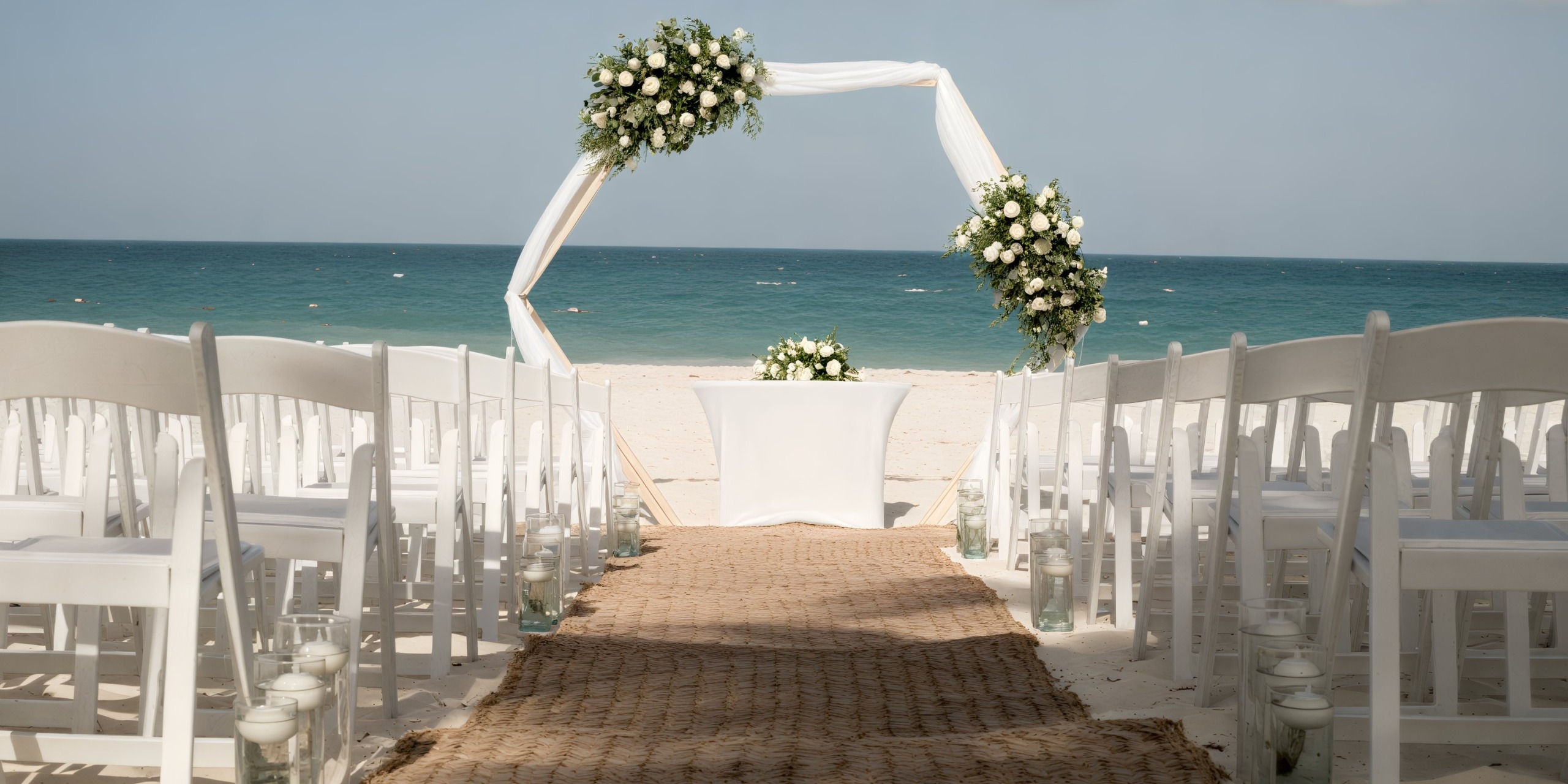 Majestic Elegance arrangement: white chairs and a floral arch set against an ocean backdrop, perfect for a destination wedding on the beach.
