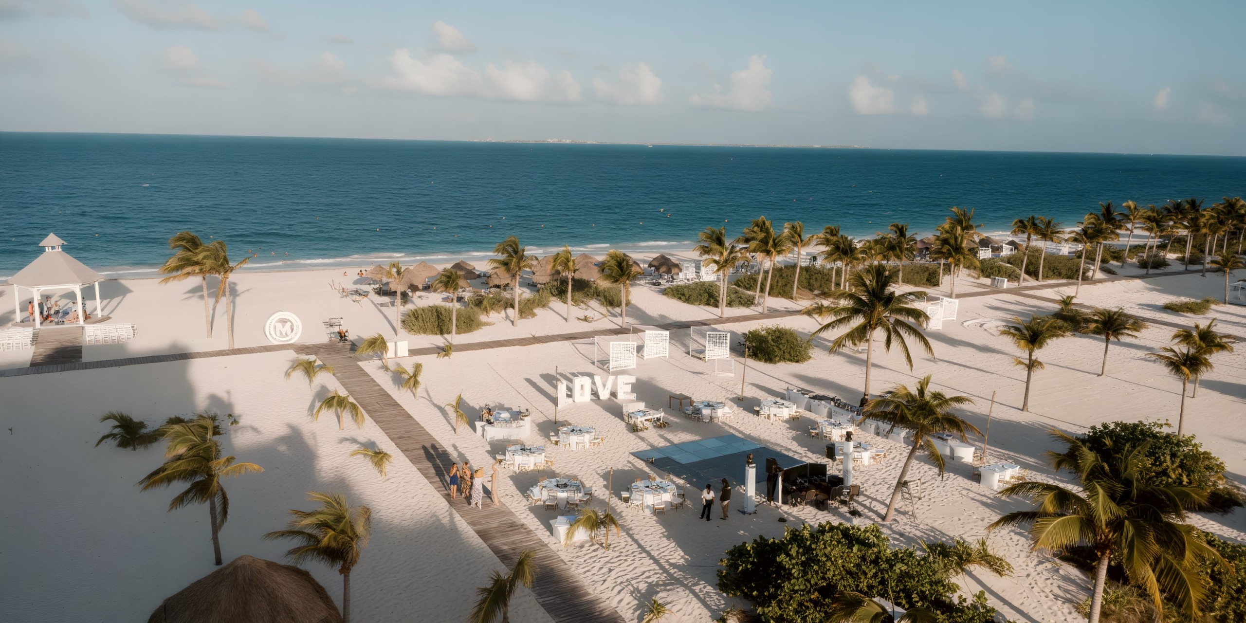 Aerial view of Majestic Elegance Costa Mujeres set for a destination wedding with palm trees and white sand.