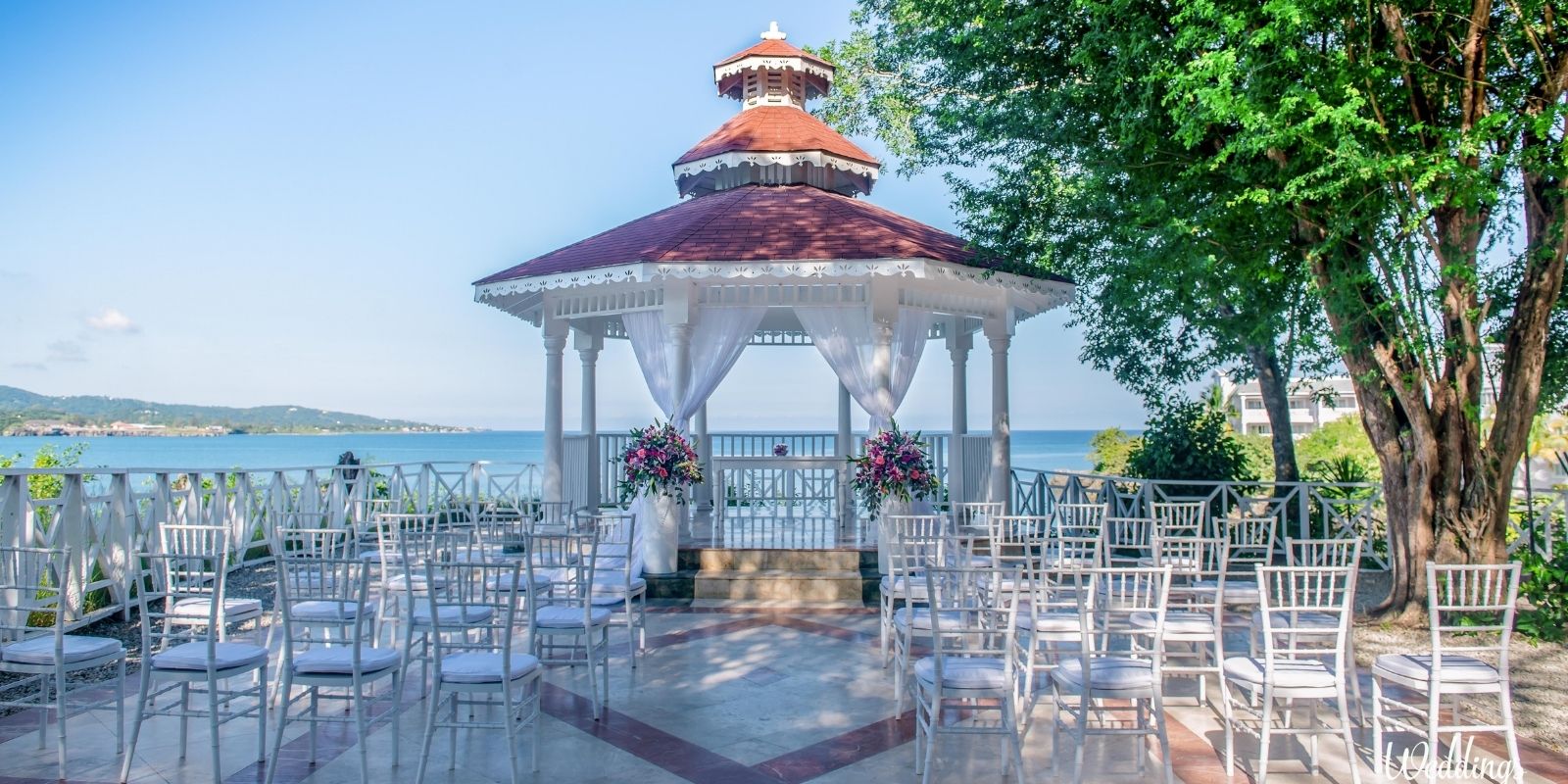 Destination wedding at the Grand Palladium Jamaica, decorated with flowers and overlooking the sea, surrounded by white chairs.