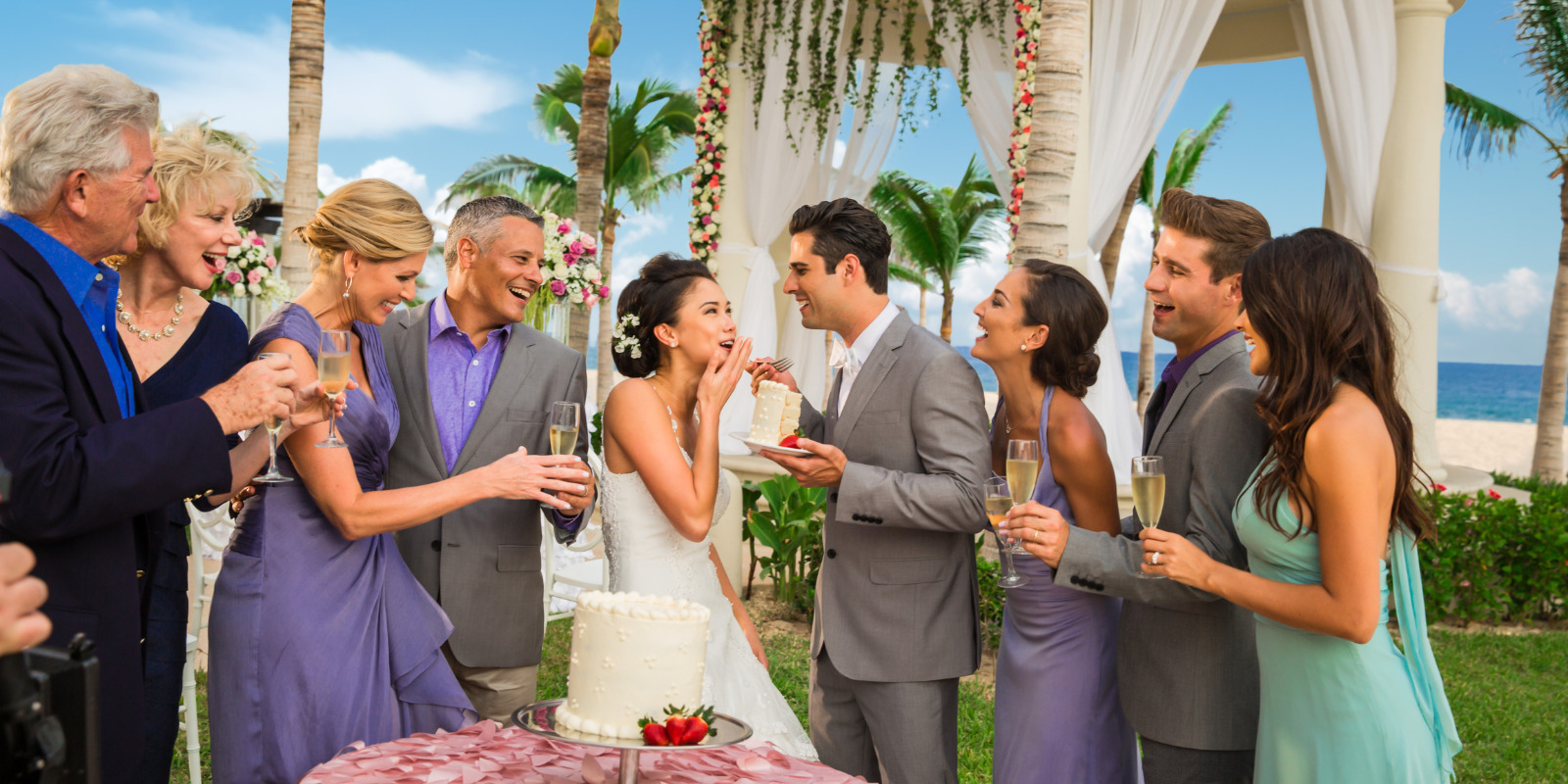 A group of people cutting a cake at an outdoor destination wedding at Hyatt Ziva Los Cabos.
