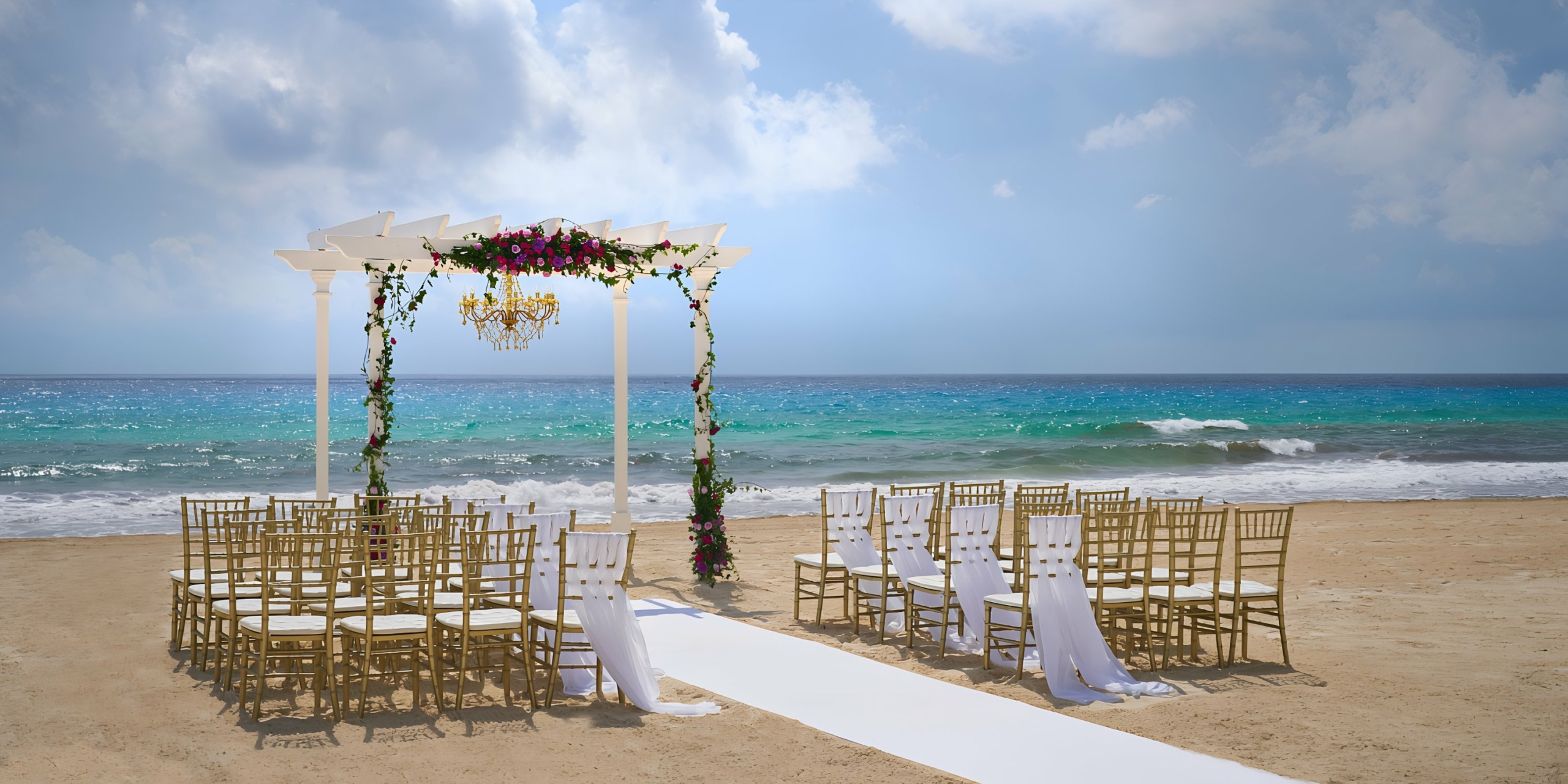 Hyatt Ziva Cancun wedding ceremony setup with a floral arch and chairs facing the sea.