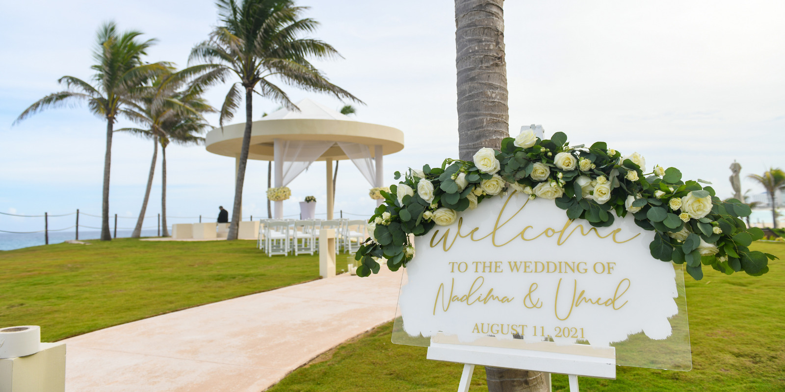 A welcome sign for a destination wedding in front of a palm tree at Hyatt Ziva Cancun on the beach.