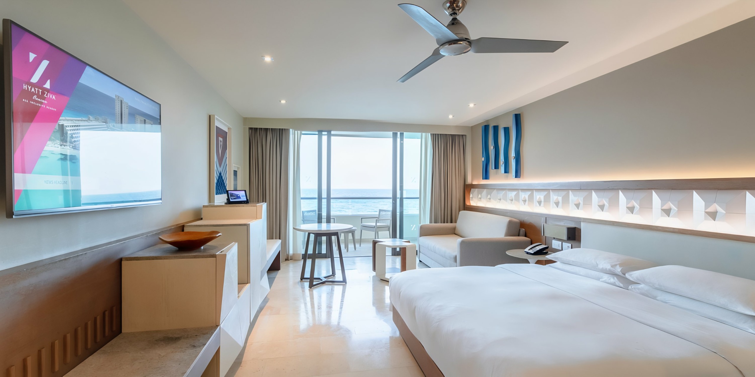 Hyatt Ziva Cancun with ocean view, featuring twin beds, a mounted tv, and a small seating area by the window.