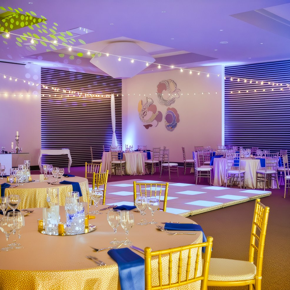 A sophisticated wedding venue featuring round tables, gold chairs, and decorative lighting to create the perfect ambiance for a destination wedding.
