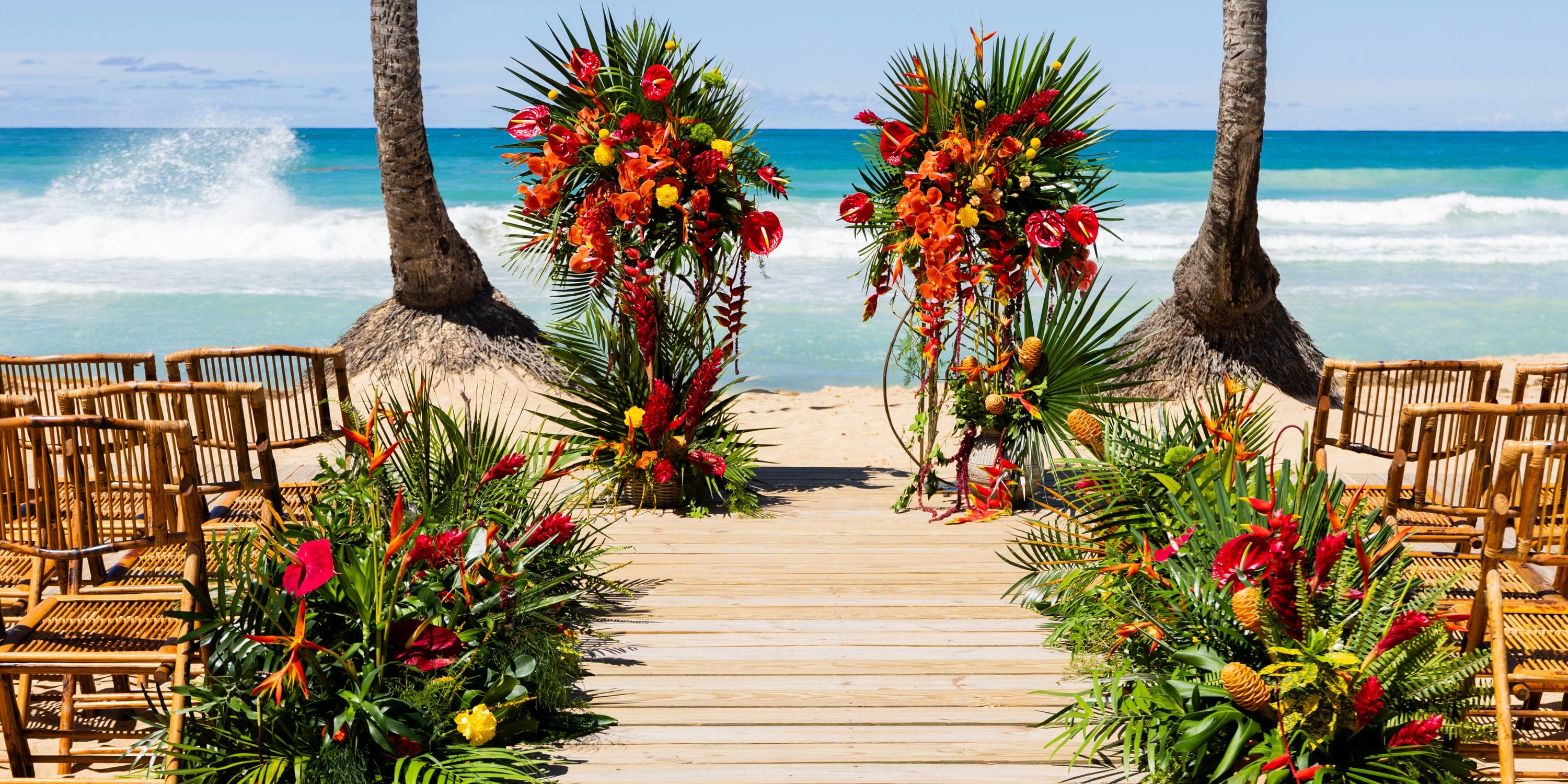 Bamboo chairs and vibrant tropical florals set for a destination wedding facing the ocean at Dreams Macao.