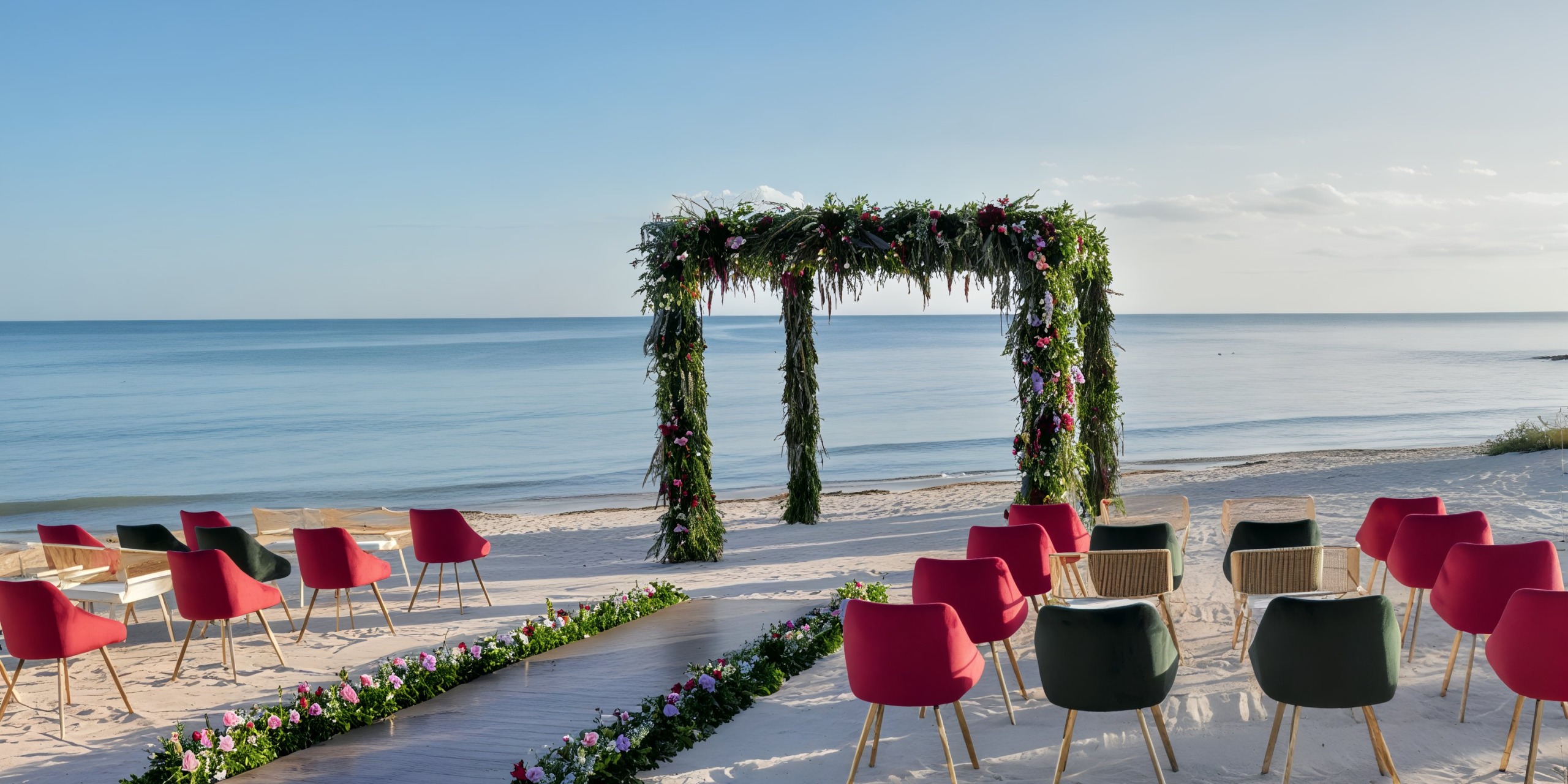 Dreams Tulum offers a stunning destination wedding setup featuring a floral arch, vibrant chairs, and the breathtaking backdrop of the sea.