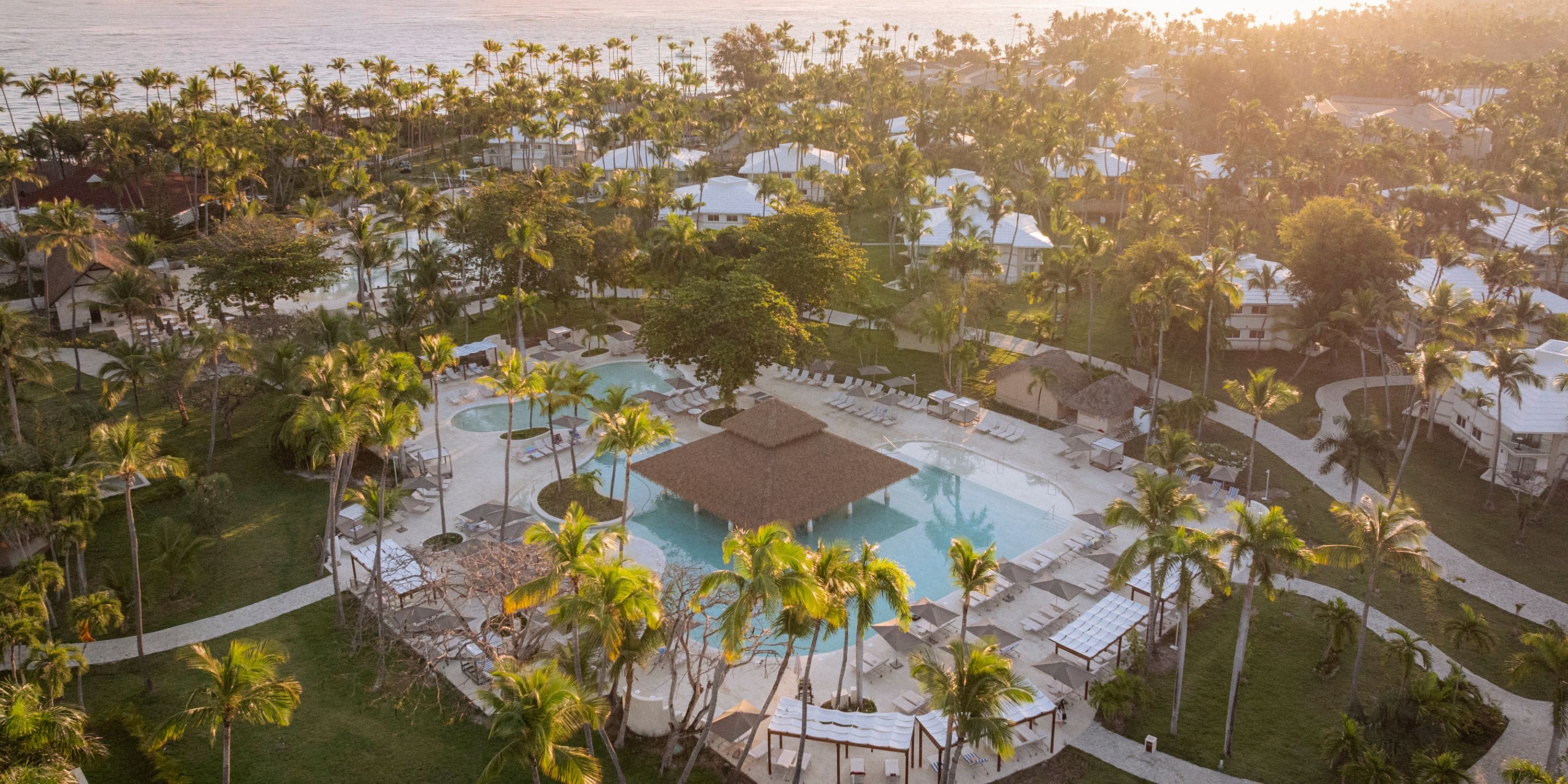 Aerial view of Grand Palladium Bavaro resort, a stunning destination wedding spot with pool and palm trees at sunset.