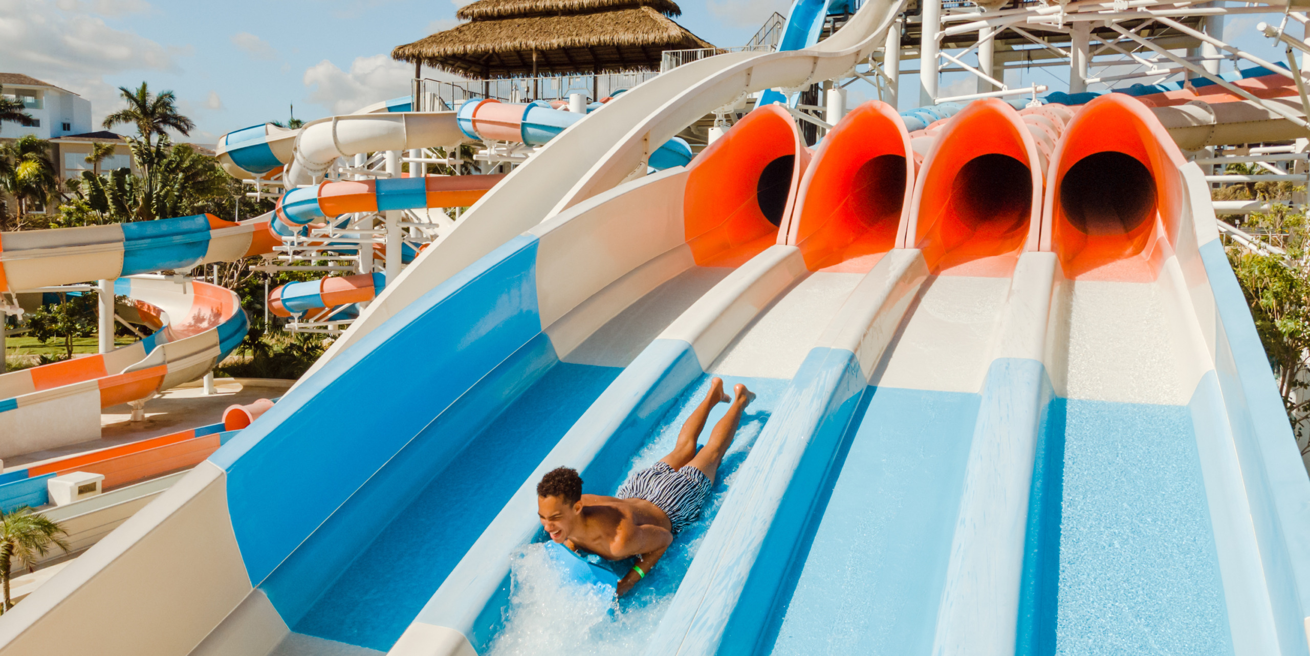 At the Hard Rock Punta Cana, a person zips down a vibrant water slide amidst an array of other slides and tropical-themed attractions.
