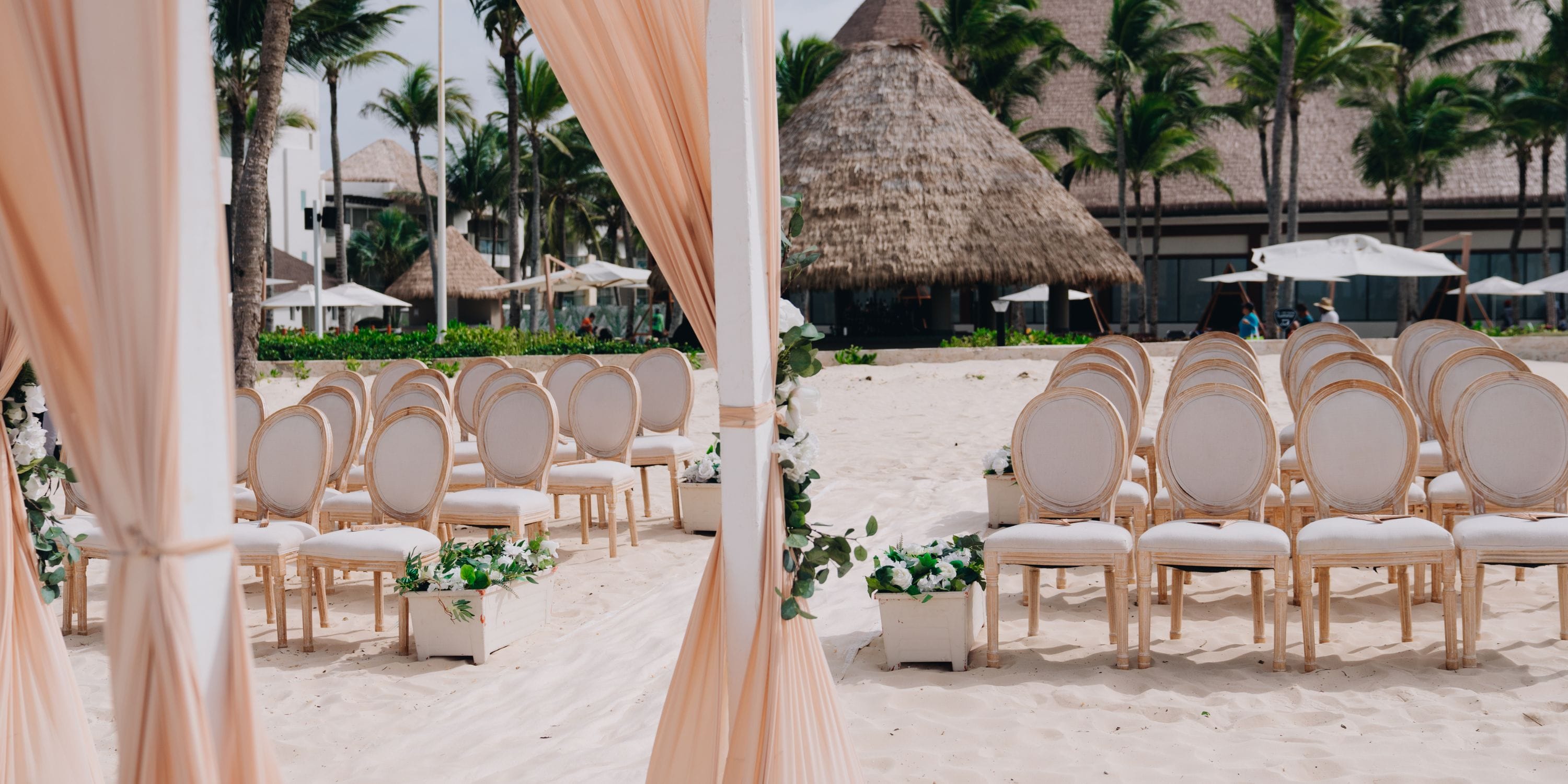 White chairs arranged on the sandy beach at Hard Rock Punta Cana for a destination wedding ceremony.