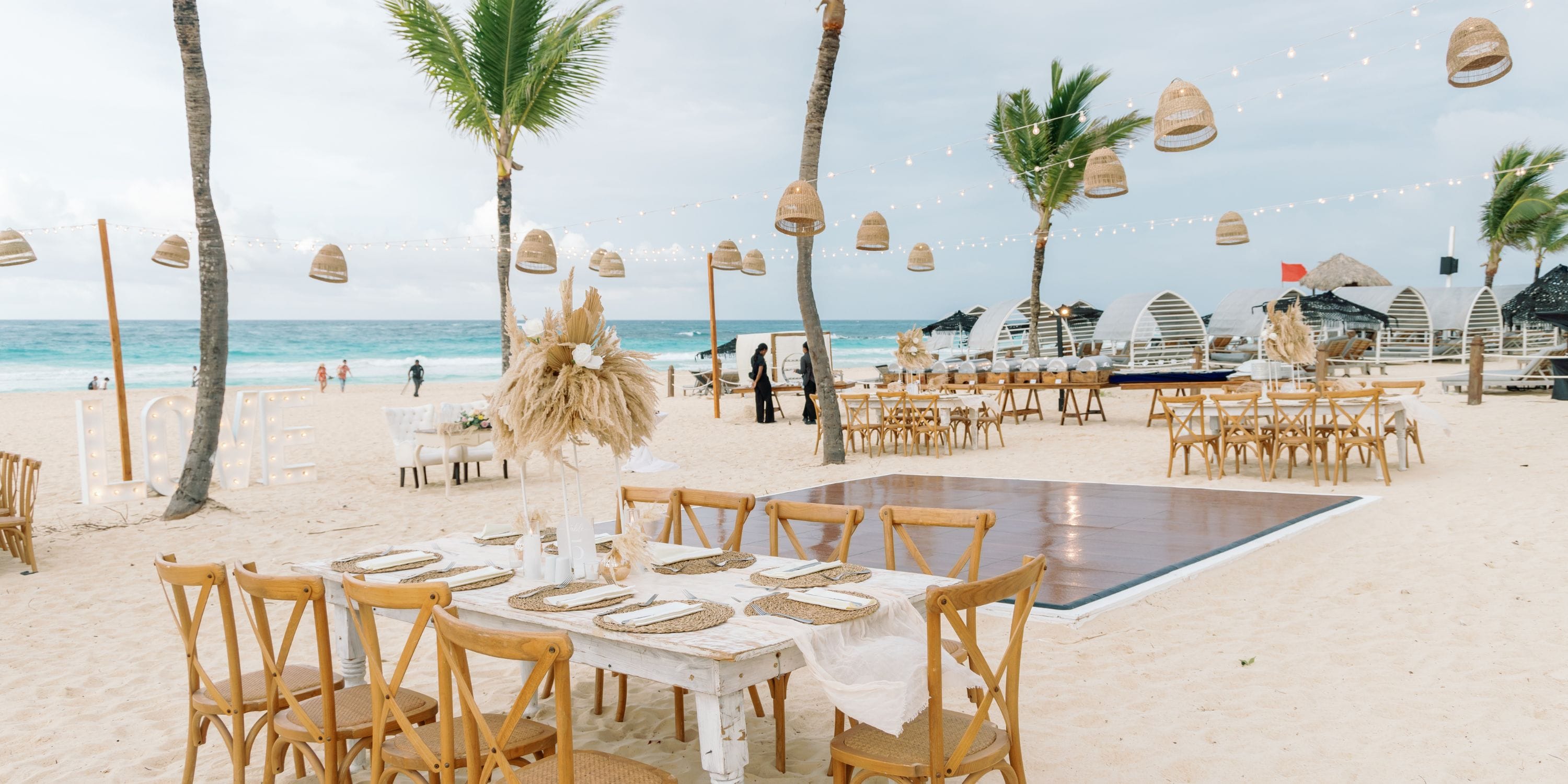 Destination wedding setup at Hard Rock Punta Cana with wooden tables, chairs, and glowing string lights.