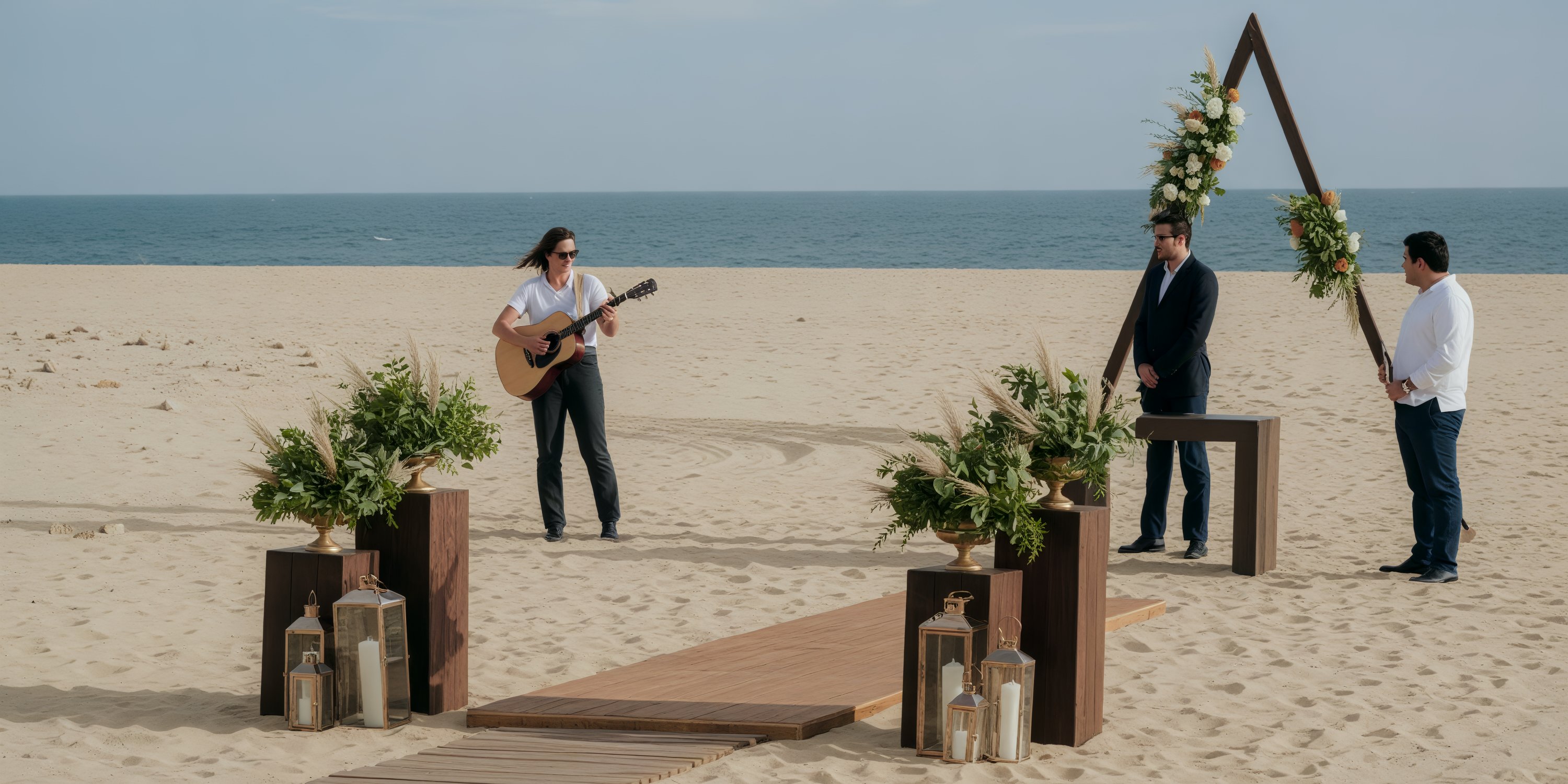 Experience your dream destination wedding at Hard Rock Los Cabos, featuring a stunning triangular arch adorned with lush plants and softly glowing lanterns, all set to the rhythm of beautiful music by the beach.