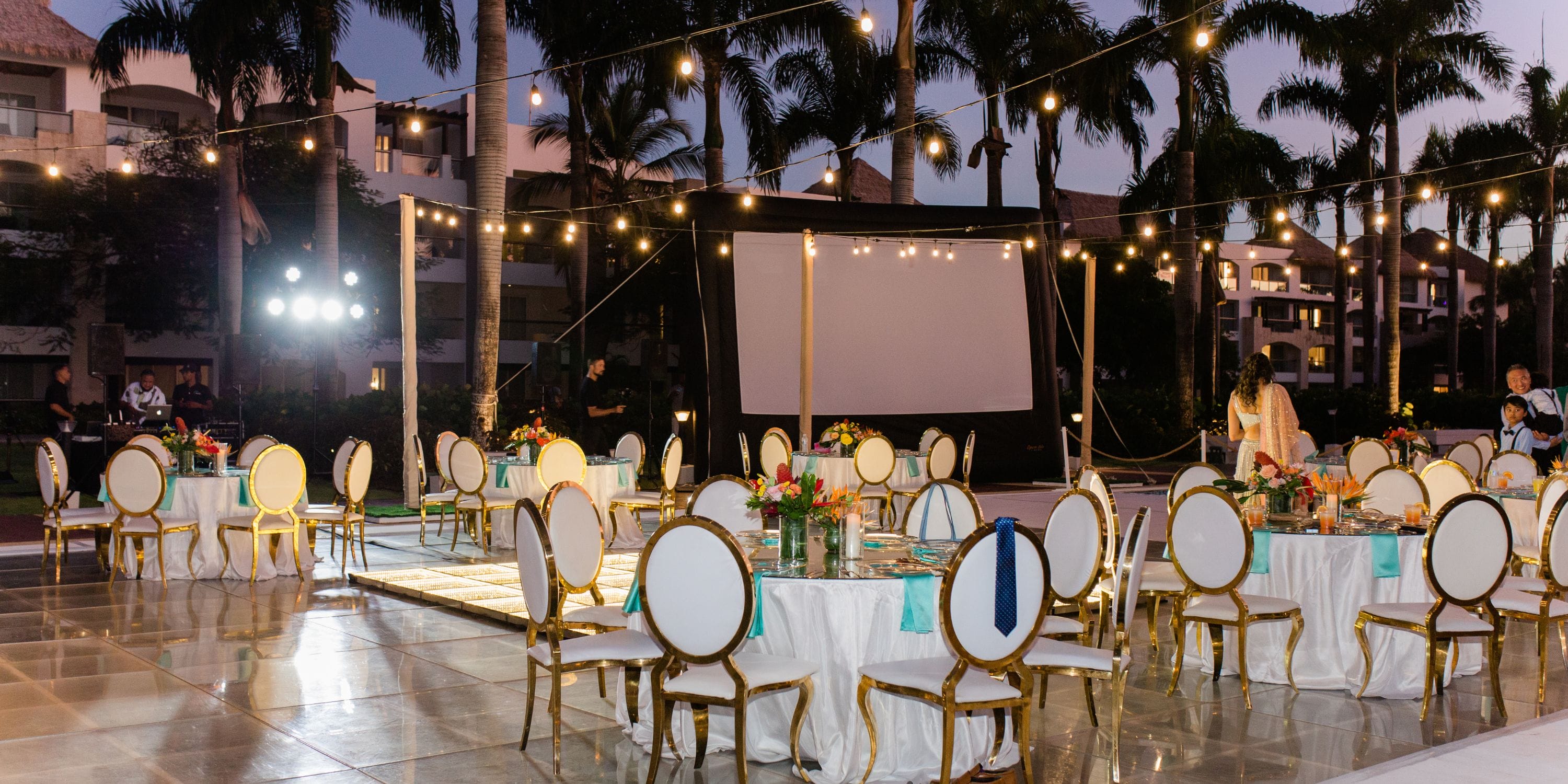 Destination wedding setup at Hard Rock Punta Cana with round tables, white chairs, string lights, and a screen.