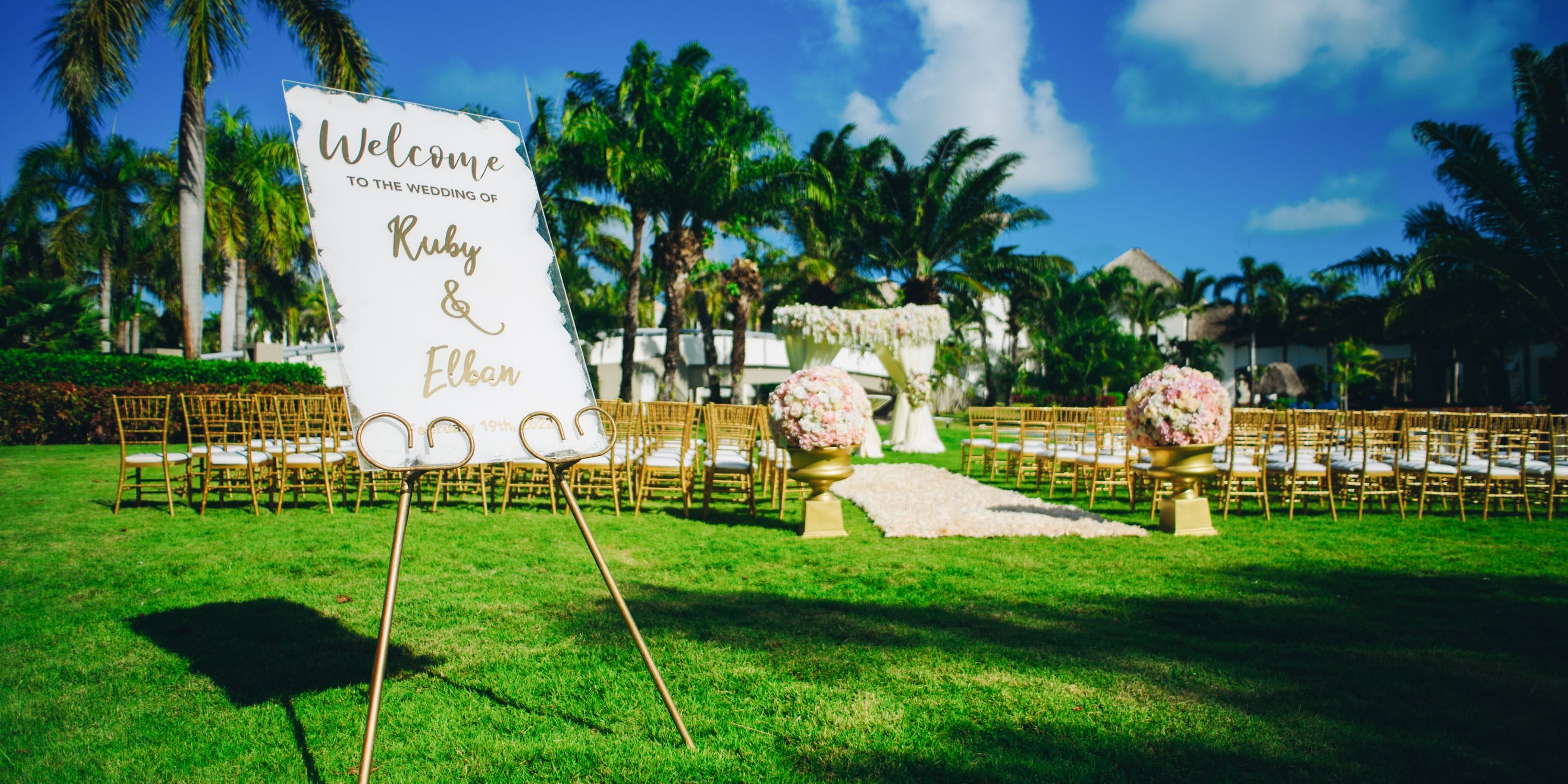 Outdoor destination wedding at Hard Rock Punta Cana with chairs, floral decor, and a welcome sign on lawn.