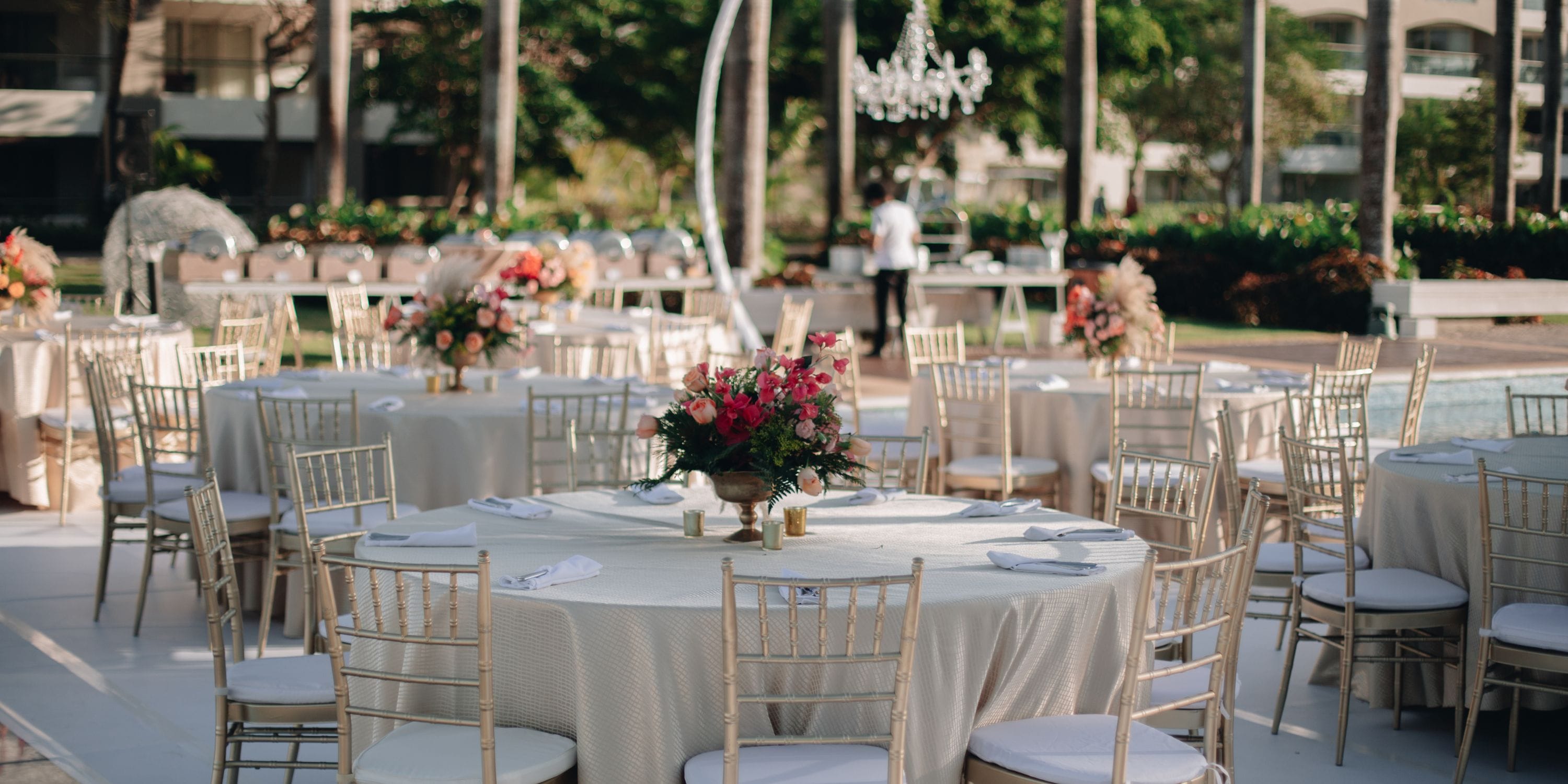 Destination wedding setup at Hard Rock Punta Cana featuring round tables, floral centerpieces, and gold chairs.