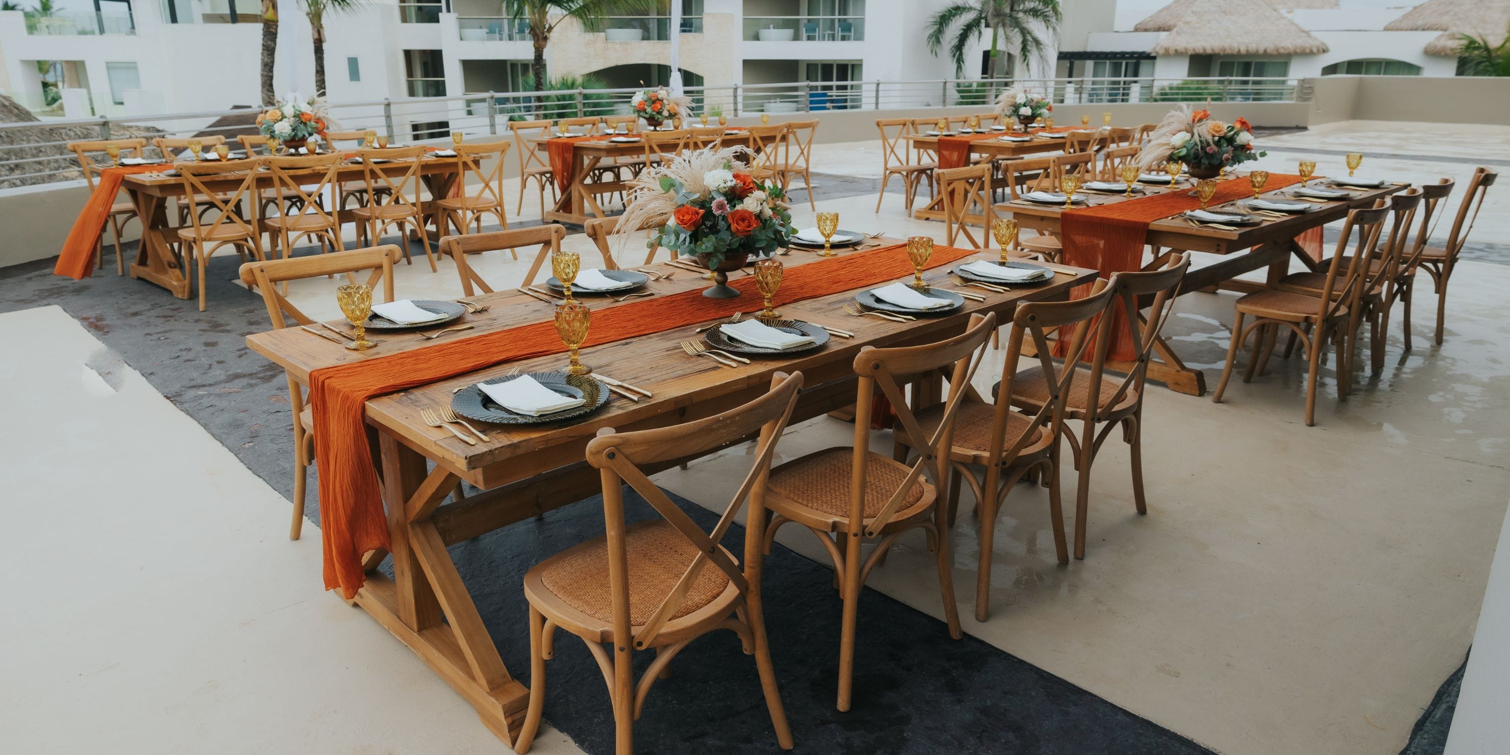 Outdoor tables at Hard Rock Punta Cana set for a destination wedding with plates, glasses, and orange runners.