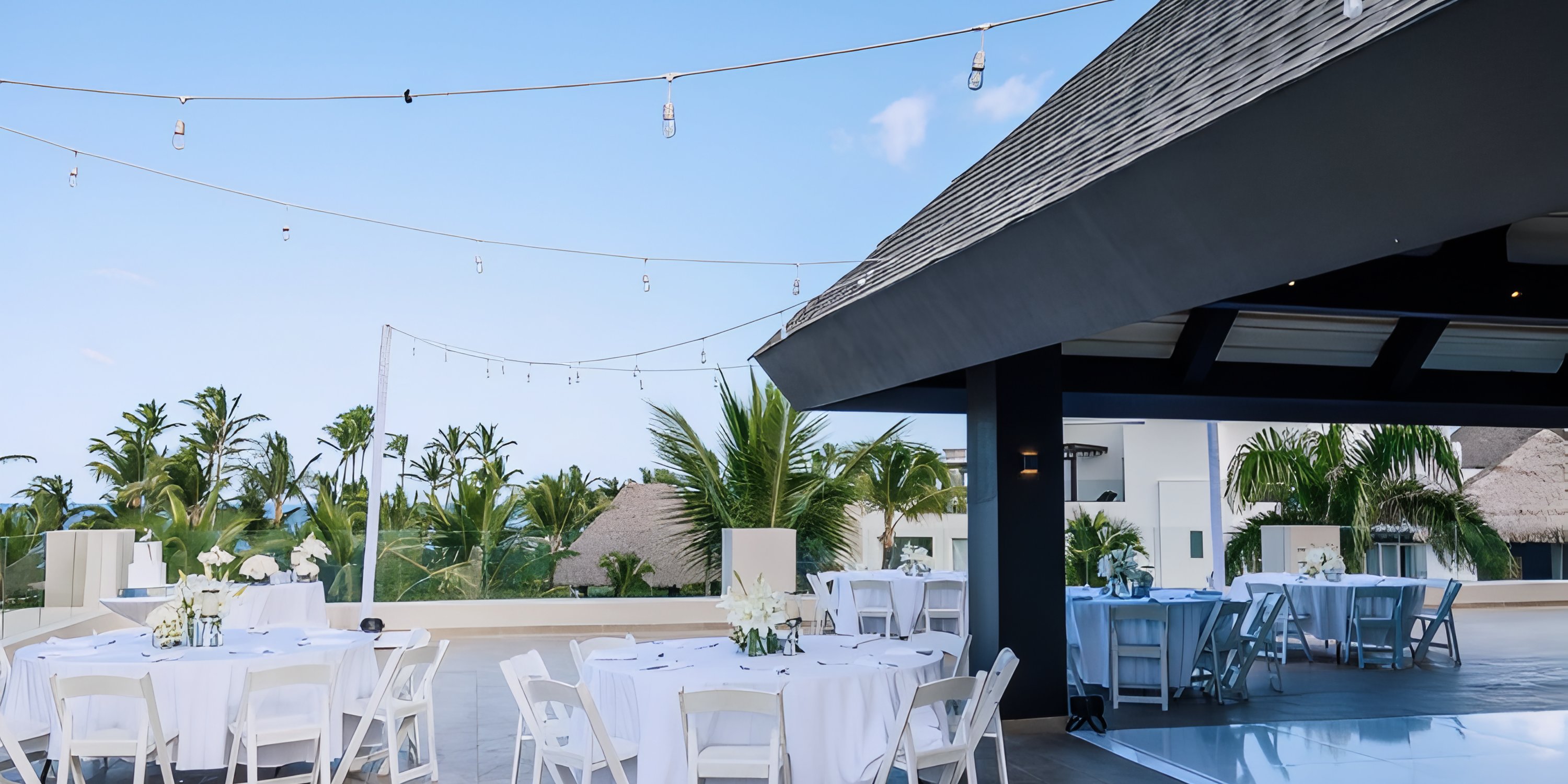 Rooftop at Hard Rock Punta Cana set for a destination wedding—round tables, white chairs, string lights.