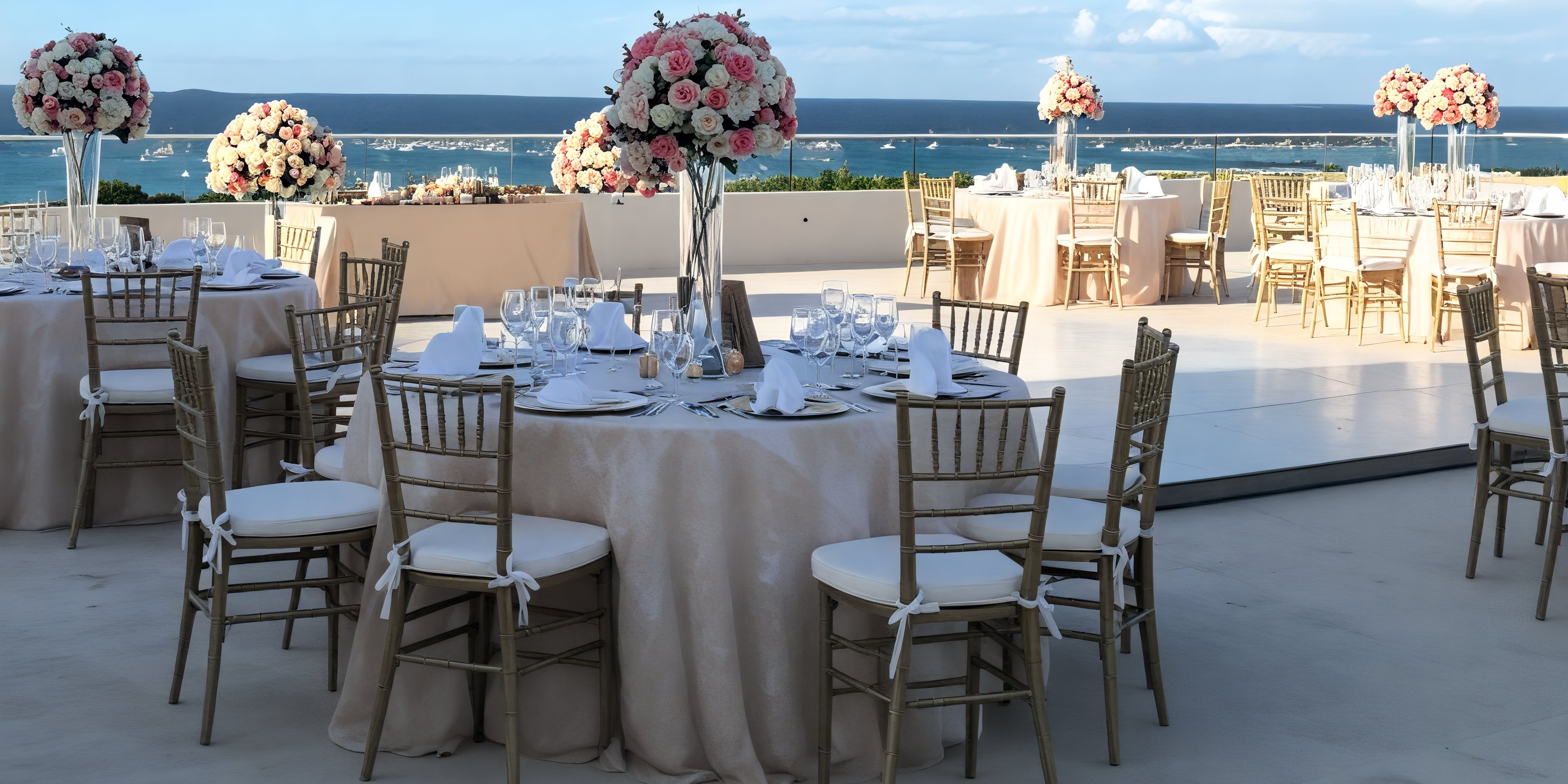 Experience a breathtaking destination wedding reception at Hyatt Ziva Cancun, featuring round tables adorned with exquisite floral centerpieces, all set against the stunning backdrop of an ocean view.