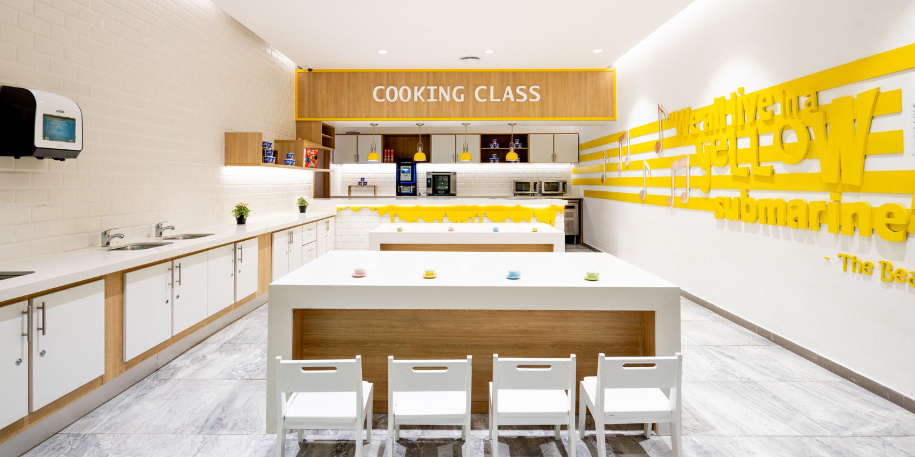 Contemporary kitchen at Hard Rock Punta Cana featuring a sign, sleek white counters, and neatly arranged small chairs—ideal for creating the perfect destination wedding setting.