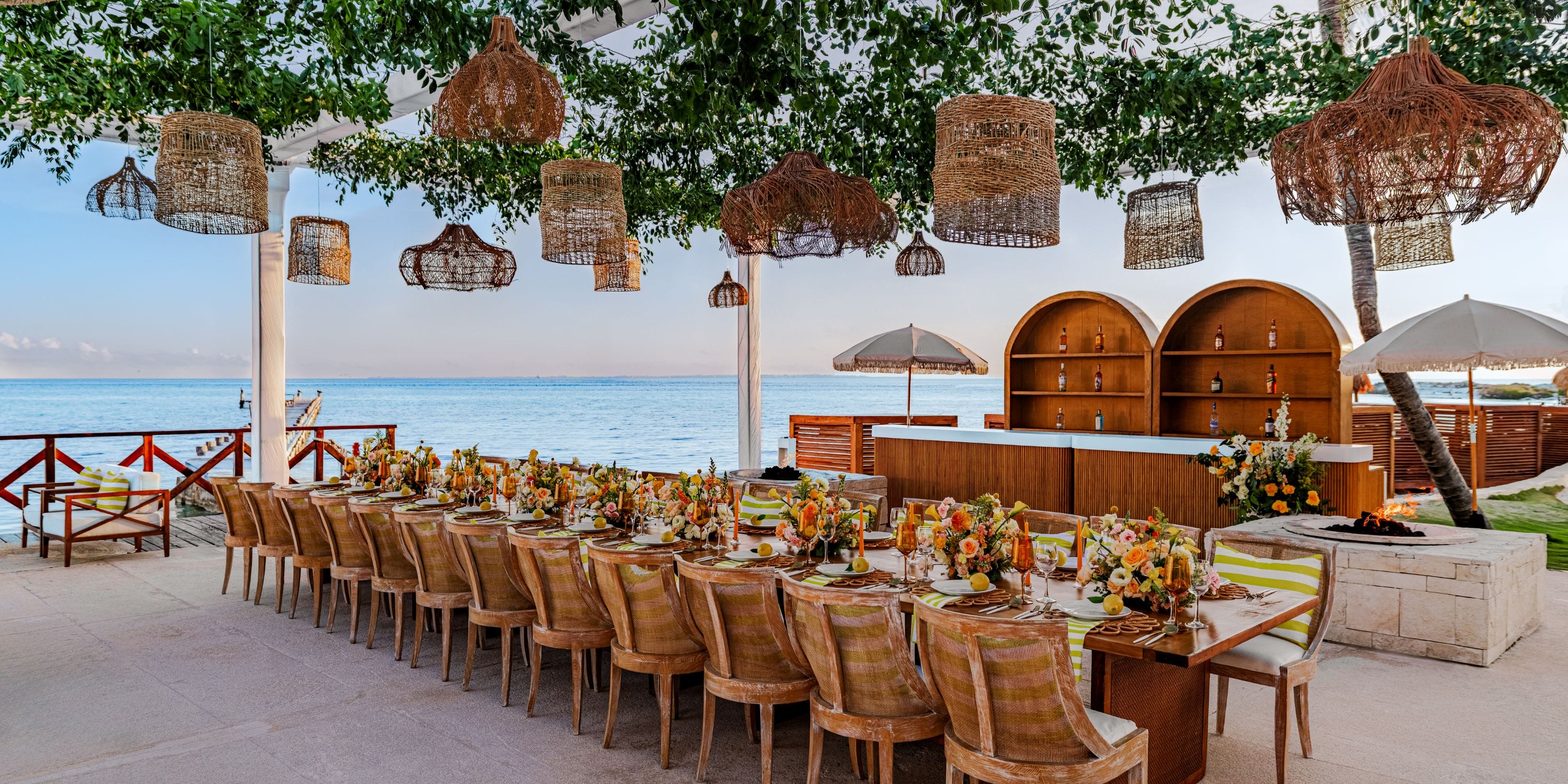 Destination wedding dining setup by the sea at Hyatt Ziva Cancun with floral decor and hanging lights.