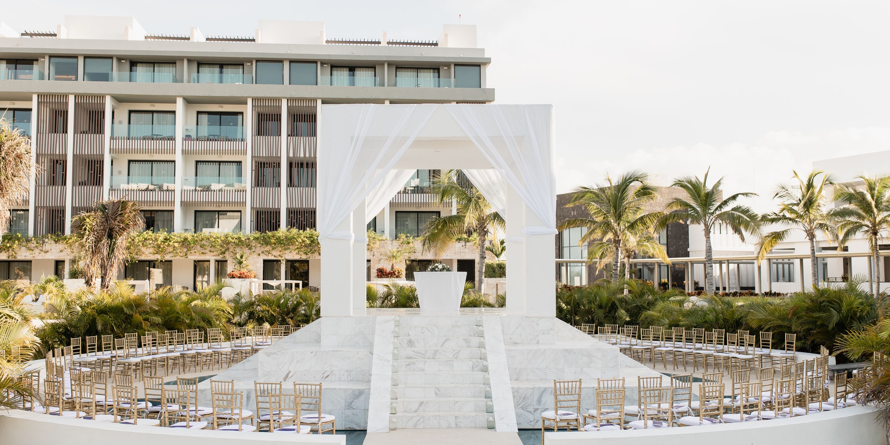 Outdoor destination wedding altar at Majestic Elegance Costa Mujeres, white drapes and marble steps.