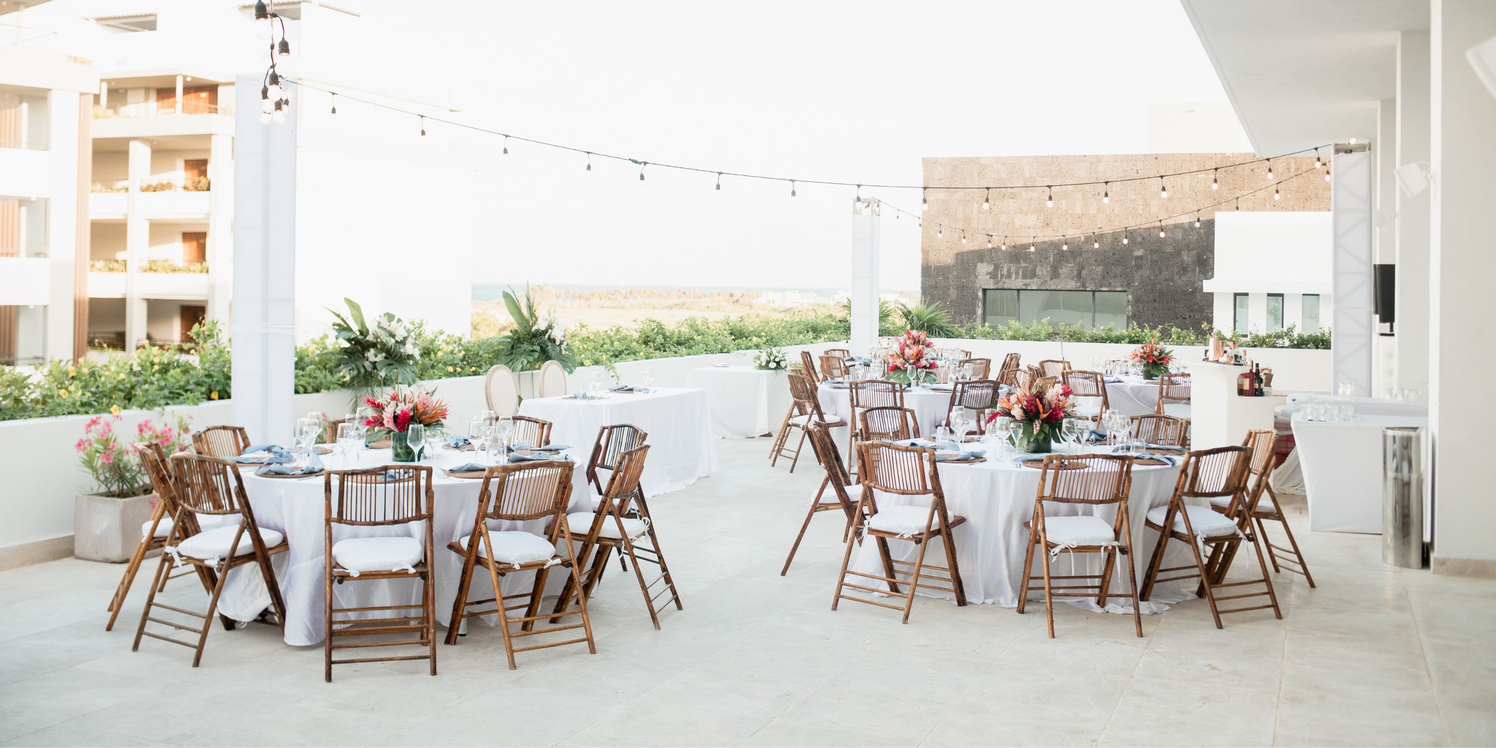 Majestic Elegance Costa Mujeres destination wedding with round tables, wooden chairs, and floral centerpieces.