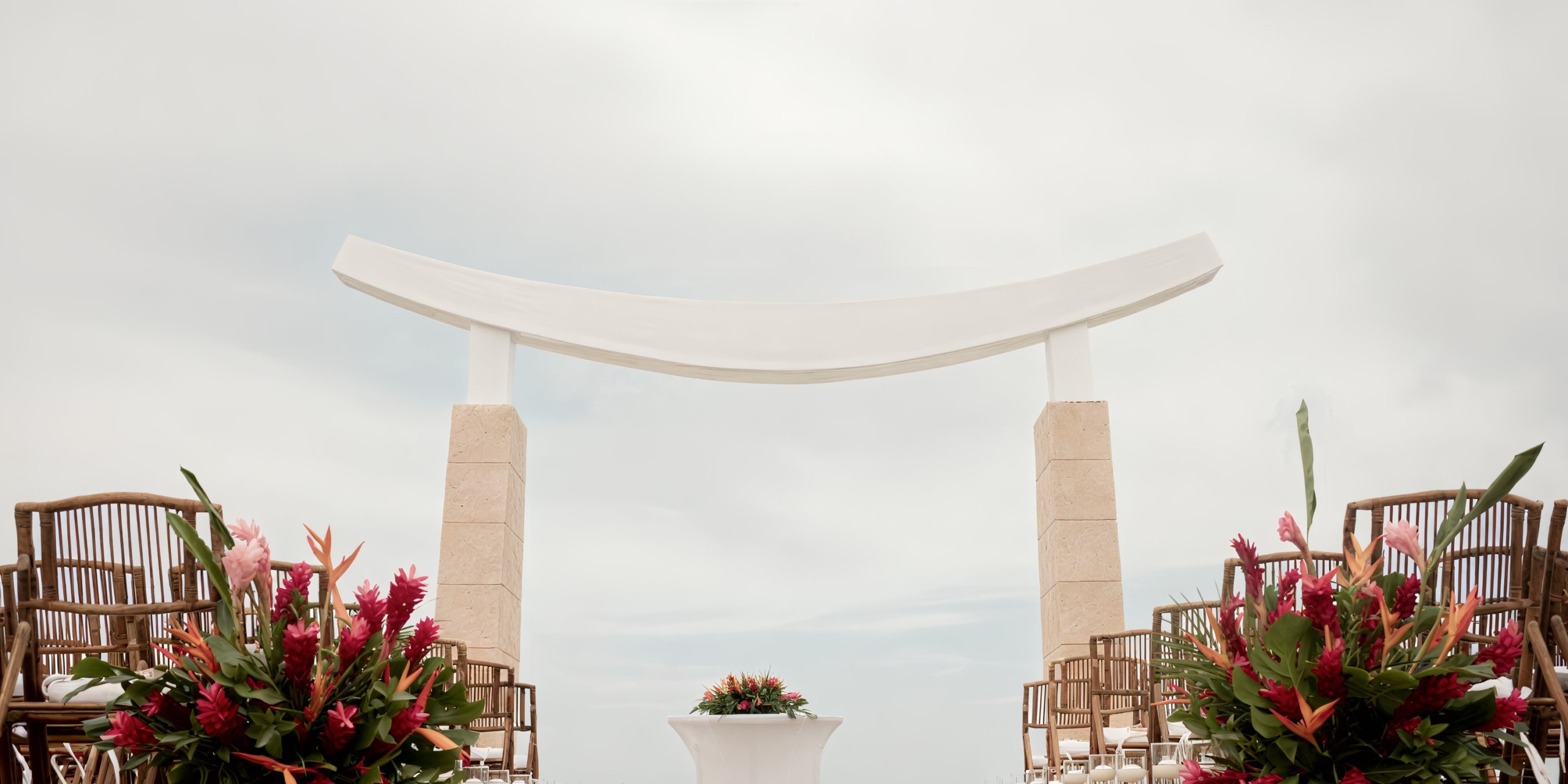 A destination wedding at Majestic Elegance Costa Mujeres features a beautiful outdoor ceremony adorned with flowers and elegant chairs, set against a backdrop of a cloudy sky.