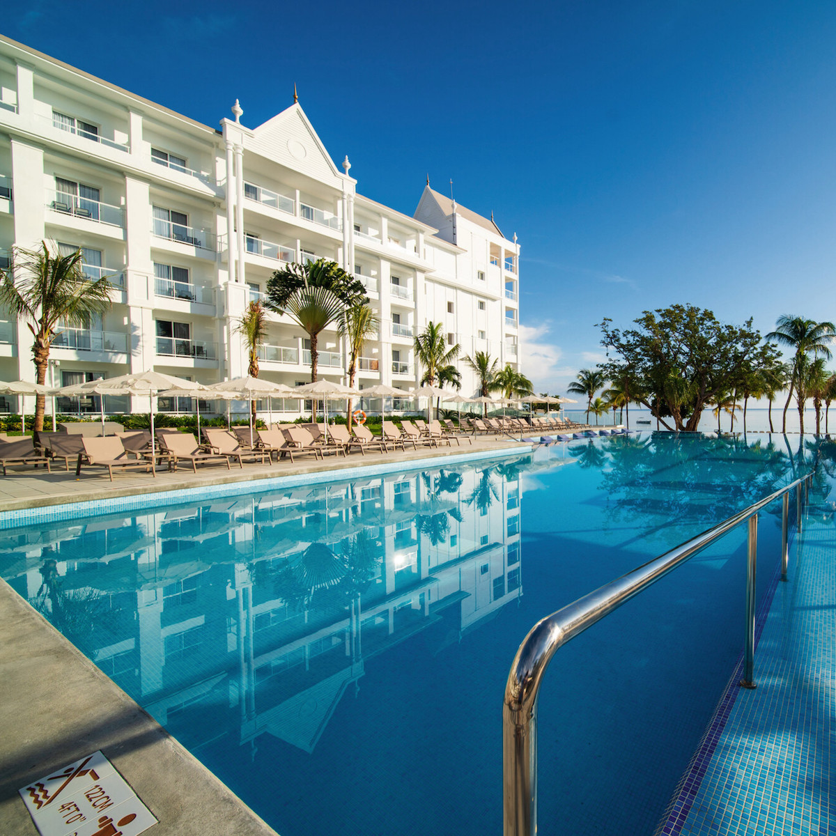 Hotel RIU Ocho Rios, perfect for destination weddings, with a large outdoor pool lined with lounge chairs under a clear blue sky.