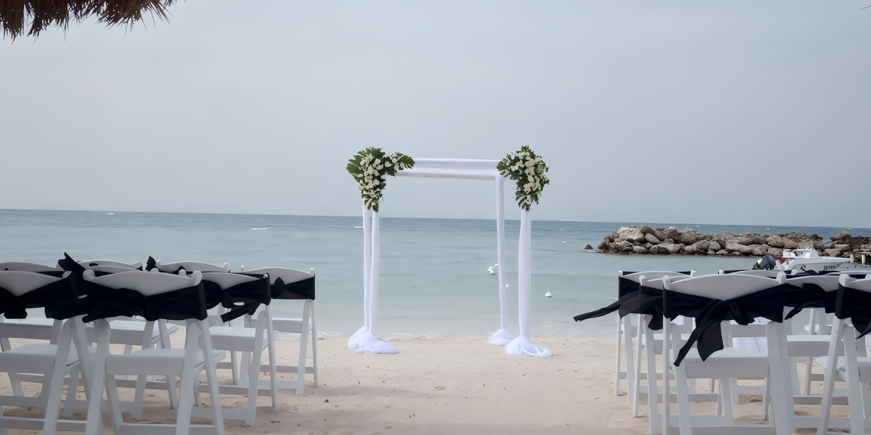 White chairs and a beautiful arch arranged on the sand for a destination wedding at Royalton Blue Waters.