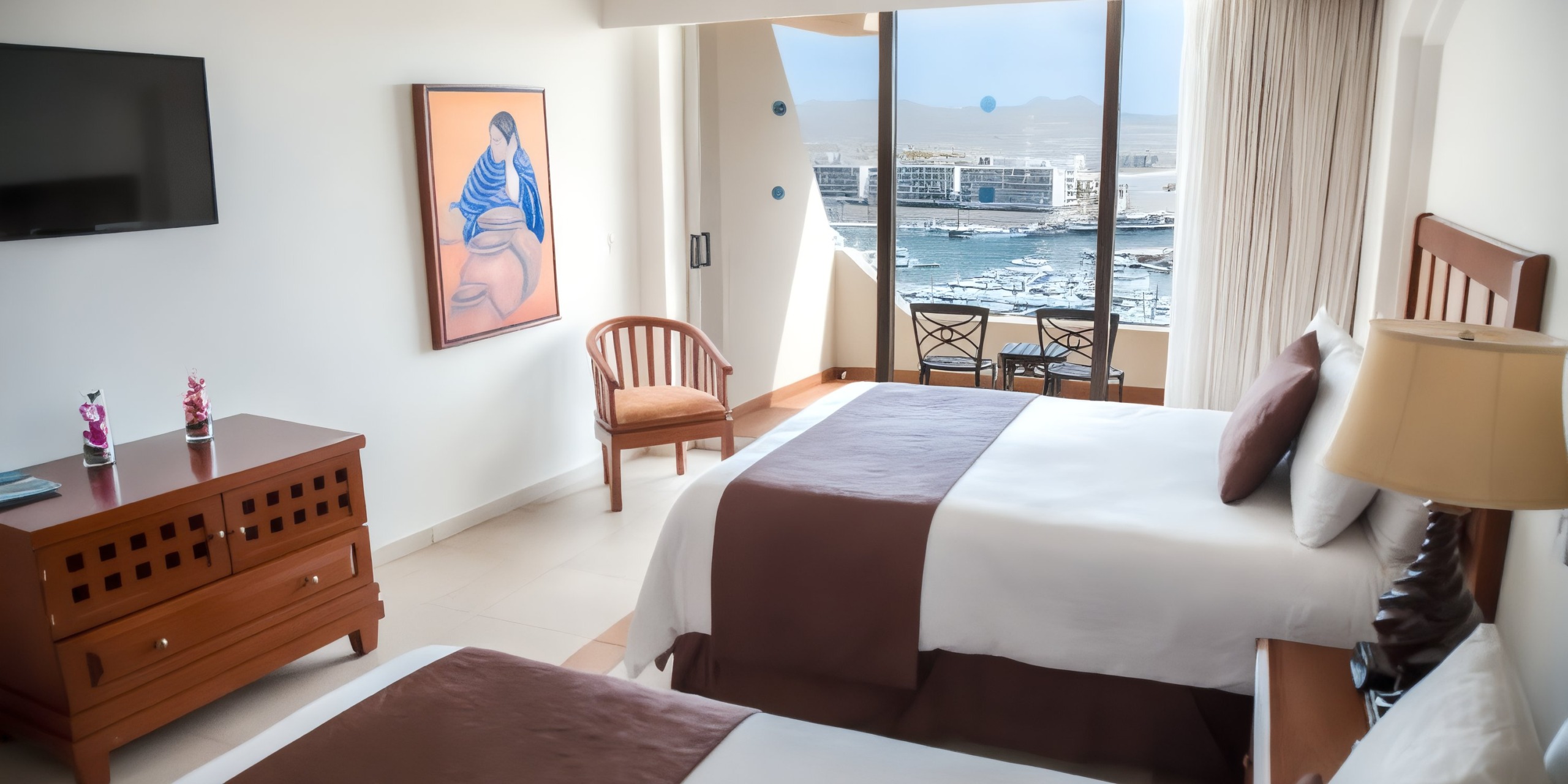 Room at Sandos Finisterra Los Cabos featuring two beds, a TV, dresser, chair, wall art, and offering a view of the harbor through large windows.