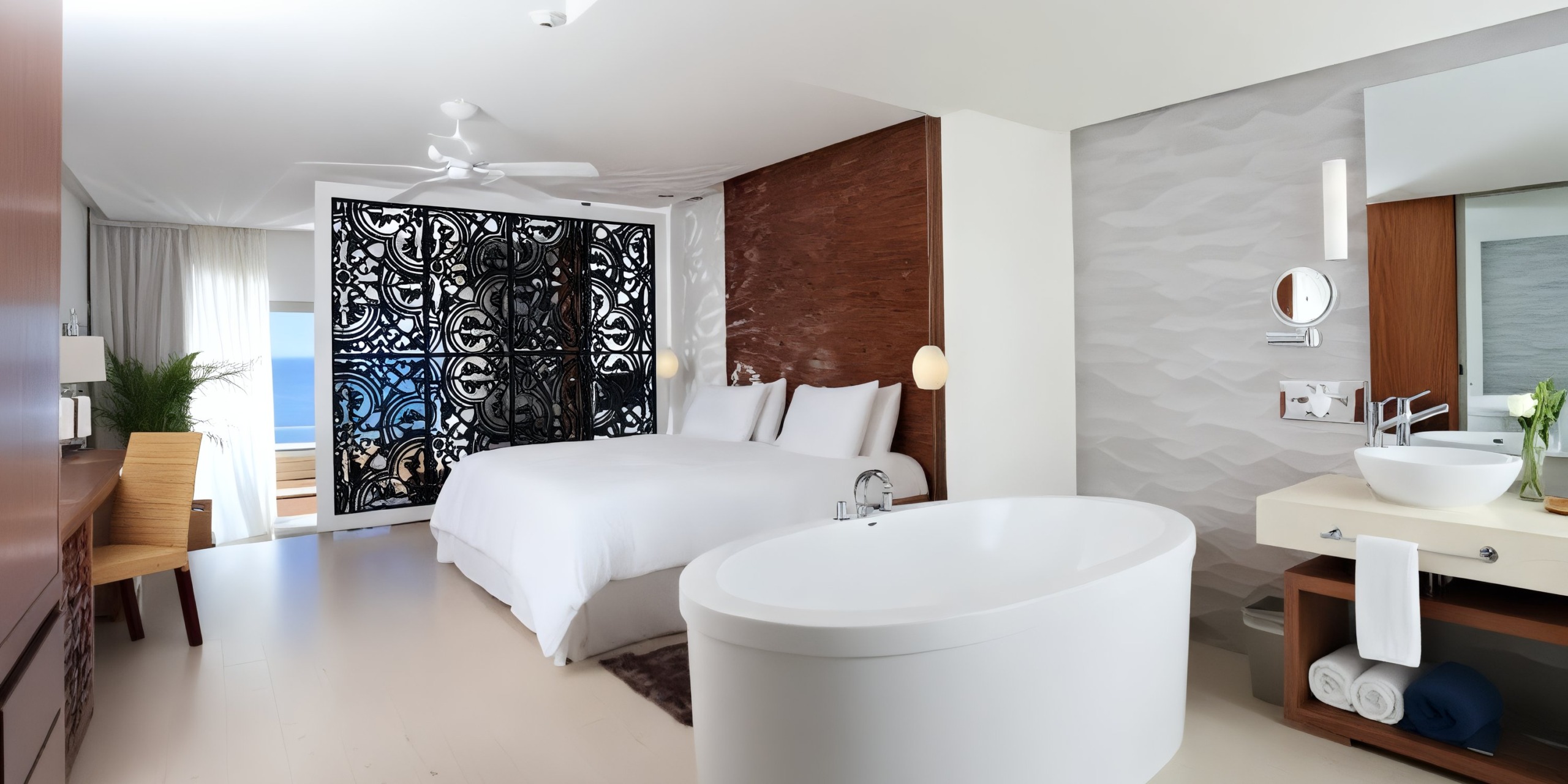 The Sandos Finisterra Los Cabos offers a modern hotel room equipped with a spacious bed, ceiling fan, and standalone bathtub. The room includes a decorative wall panel, balcony with an ocean view, a desk, and bathroom amenities.
