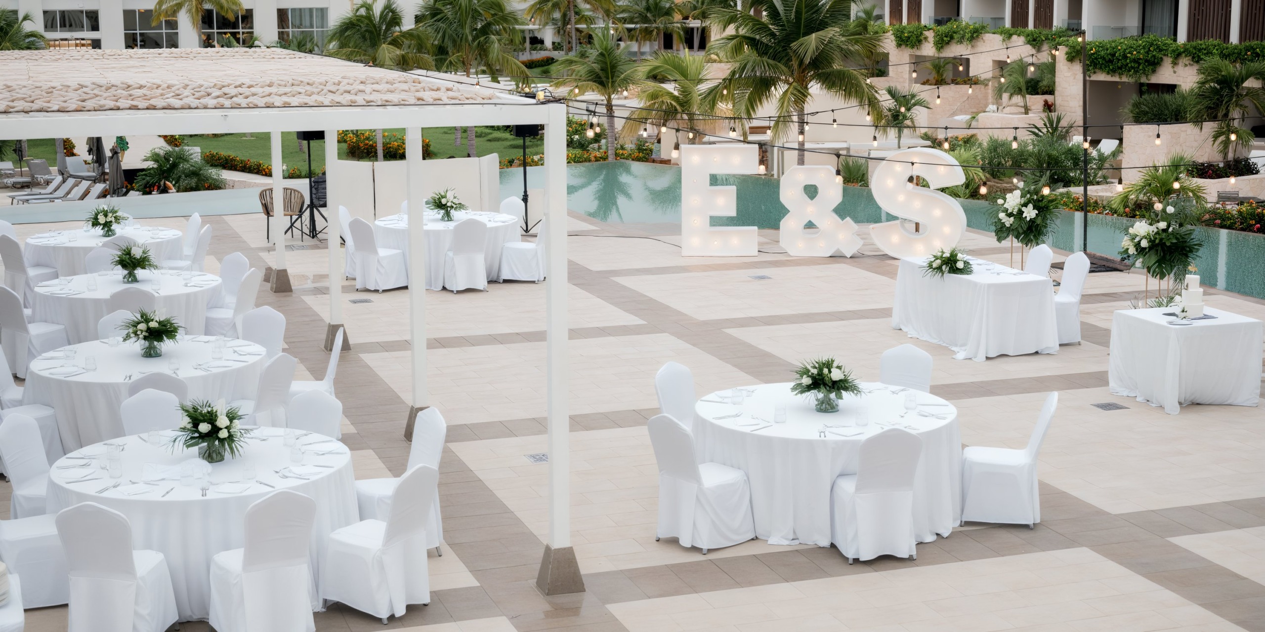 Destination wedding at Majestic Elegance Costa Mujeres: adorned with white tables and chairs, featuring elegant "E & S" letters.