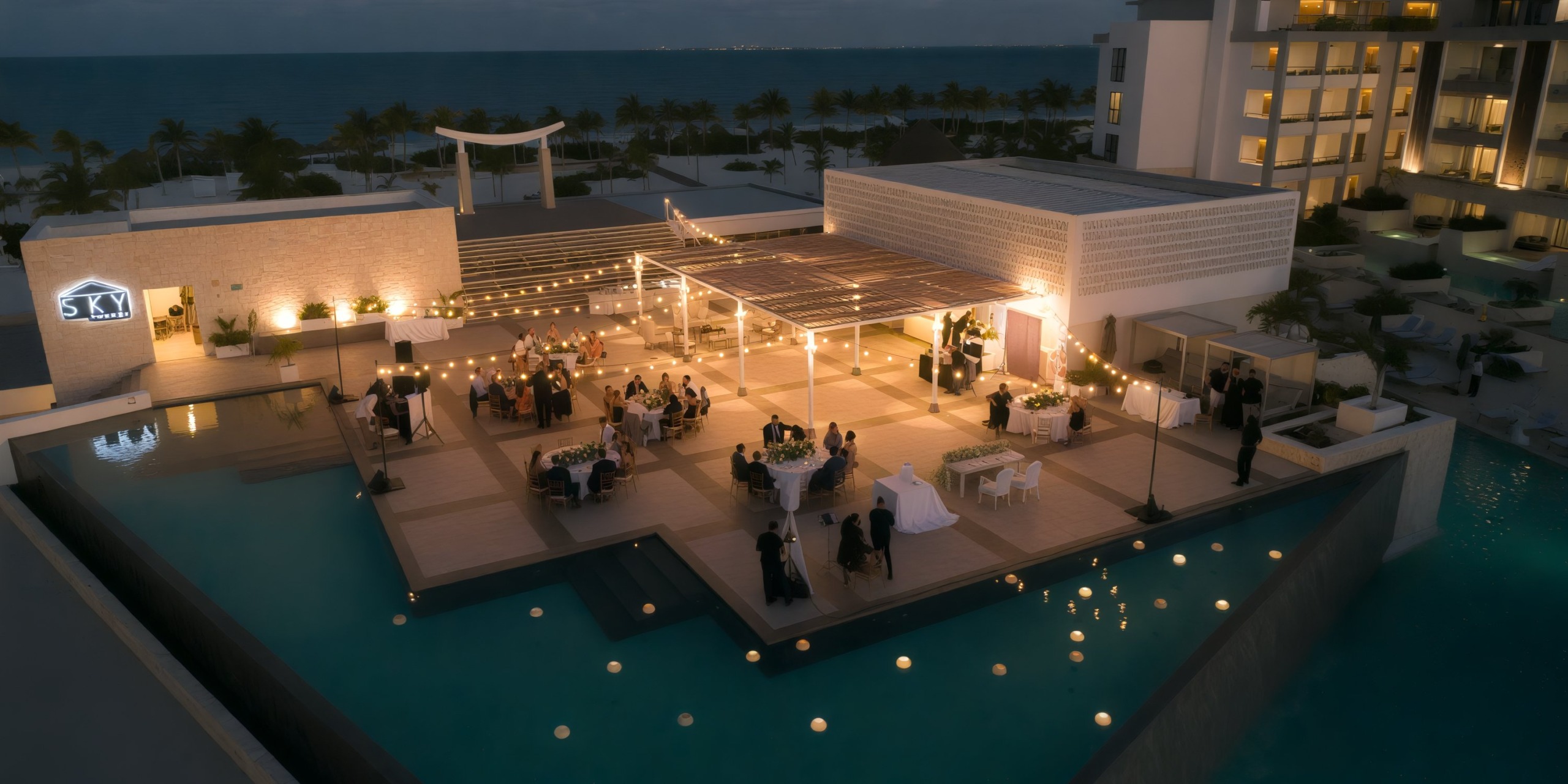 The rooftop dining area at Majestic Elegance Costa Mujeres offers a stunning setting over a pool, complete with tables, chairs, and ambient lights—perfect for a beautiful destination wedding celebration.