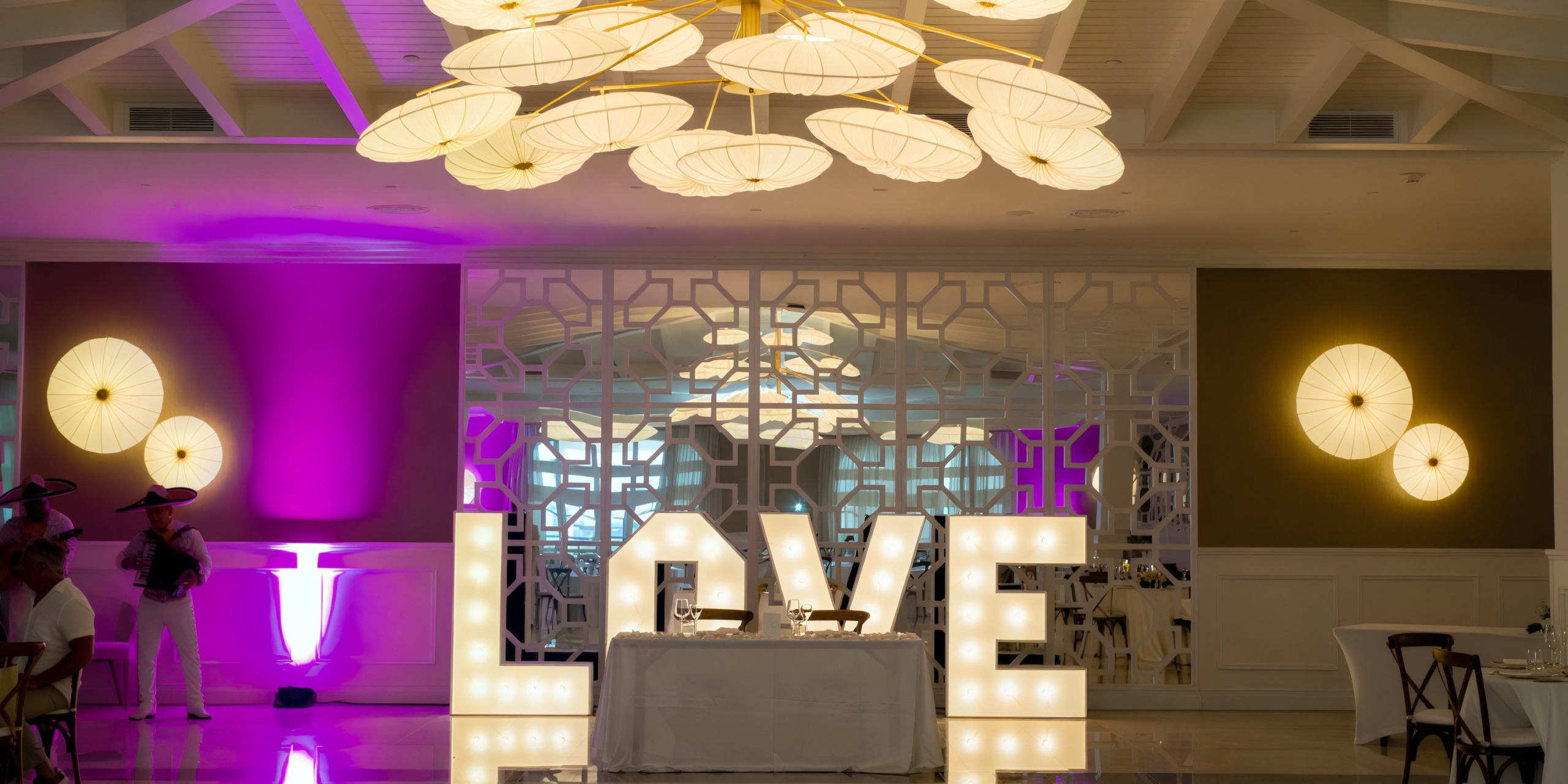 Majestic Elegance's 'LOVE' sign brilliantly illuminated in a room adorned with white and purple lighting, creating the perfect ambiance for a destination wedding.