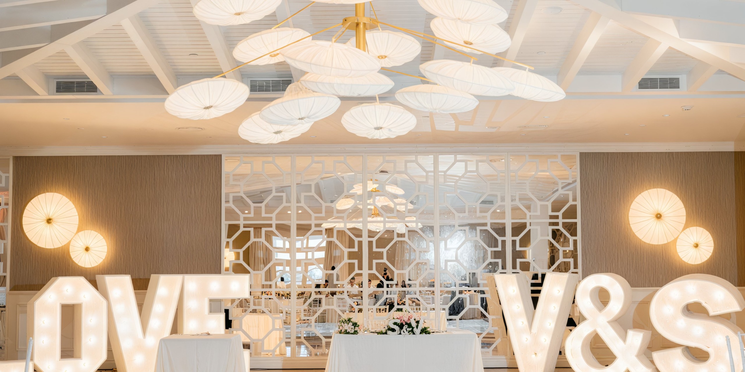 Illuminated letters spelling "LOVE" and "V & S" adorn a stylish room at Majestic Elegance Costa Mujeres, creating a romantic atmosphere perfect for a destination wedding.