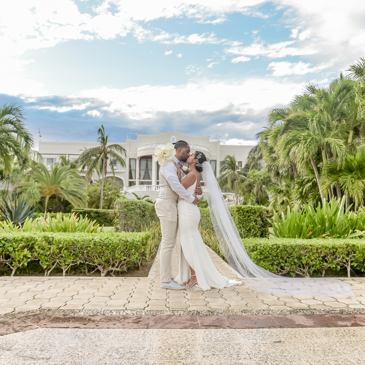 A bride and groom kiss in front of Dreams Tulum.