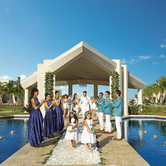 Just married couple walks down the aisle together with flower girls at the pool gazebo at Dreams Onyx Punta Cana Dominican Republic