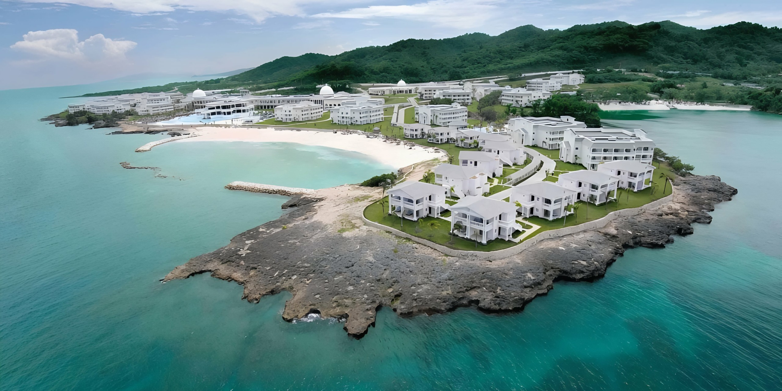 Aerial view of the Grand Palladium Lady Hamilton resort with white buildings on a rocky promontory.