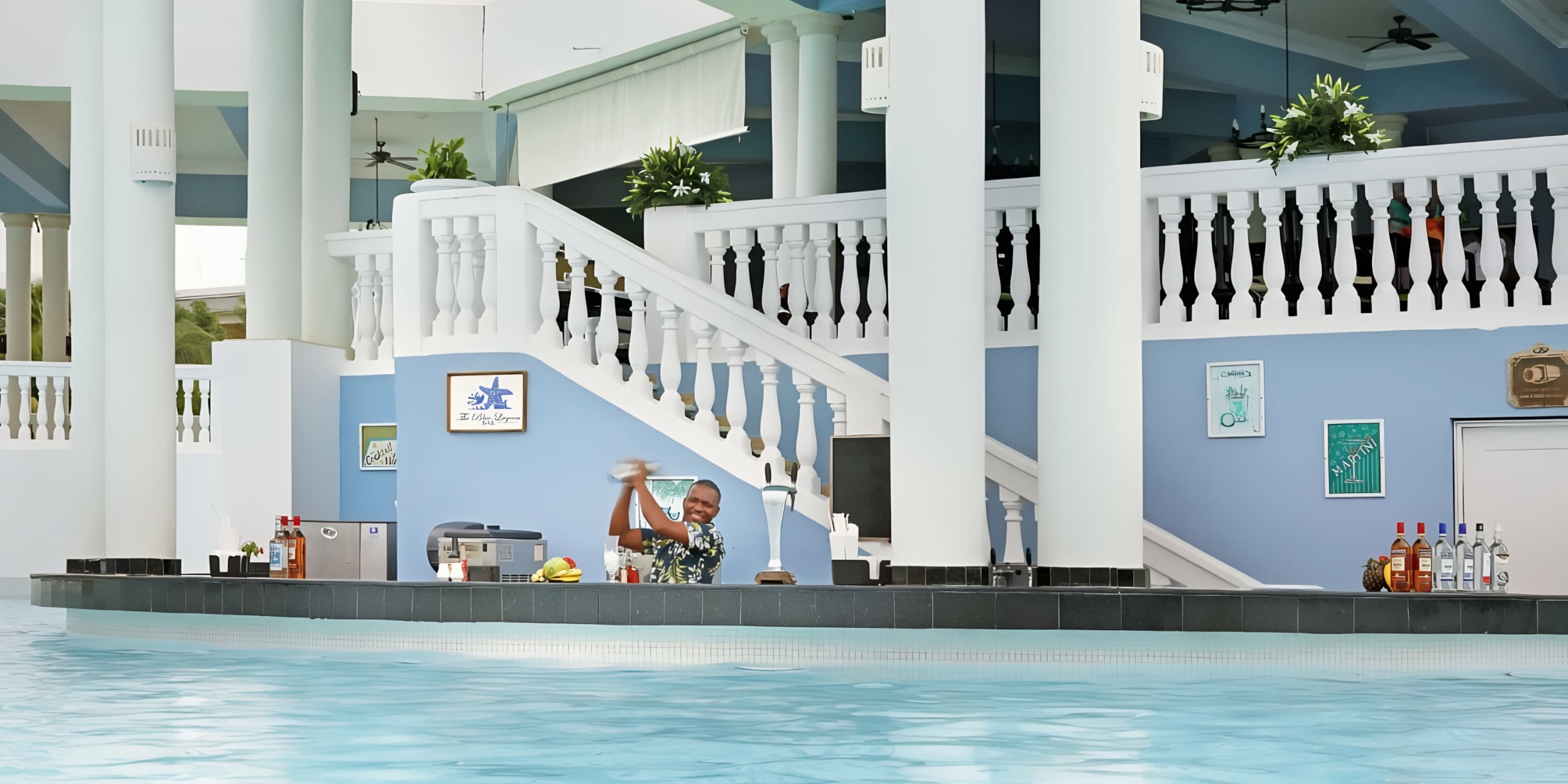Bartender performing a flair bartending trick at a swim-up pool bar during a Grand Palladium Lady Hamilton wedding.