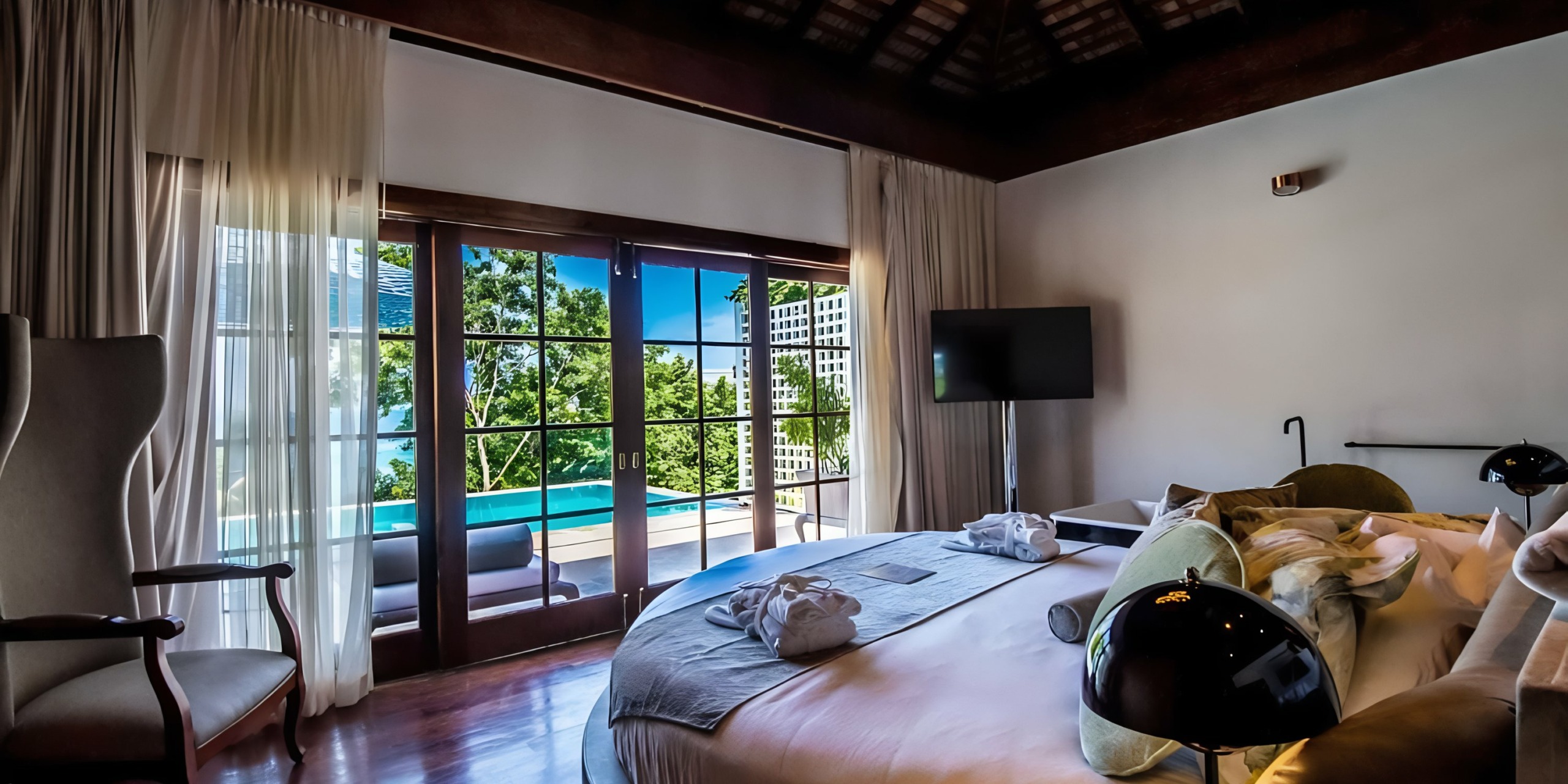 Modern Grand Palladium Lady Hamilton hotel room with a view of the pool and surrounding greenery through floor-to-ceiling windows.