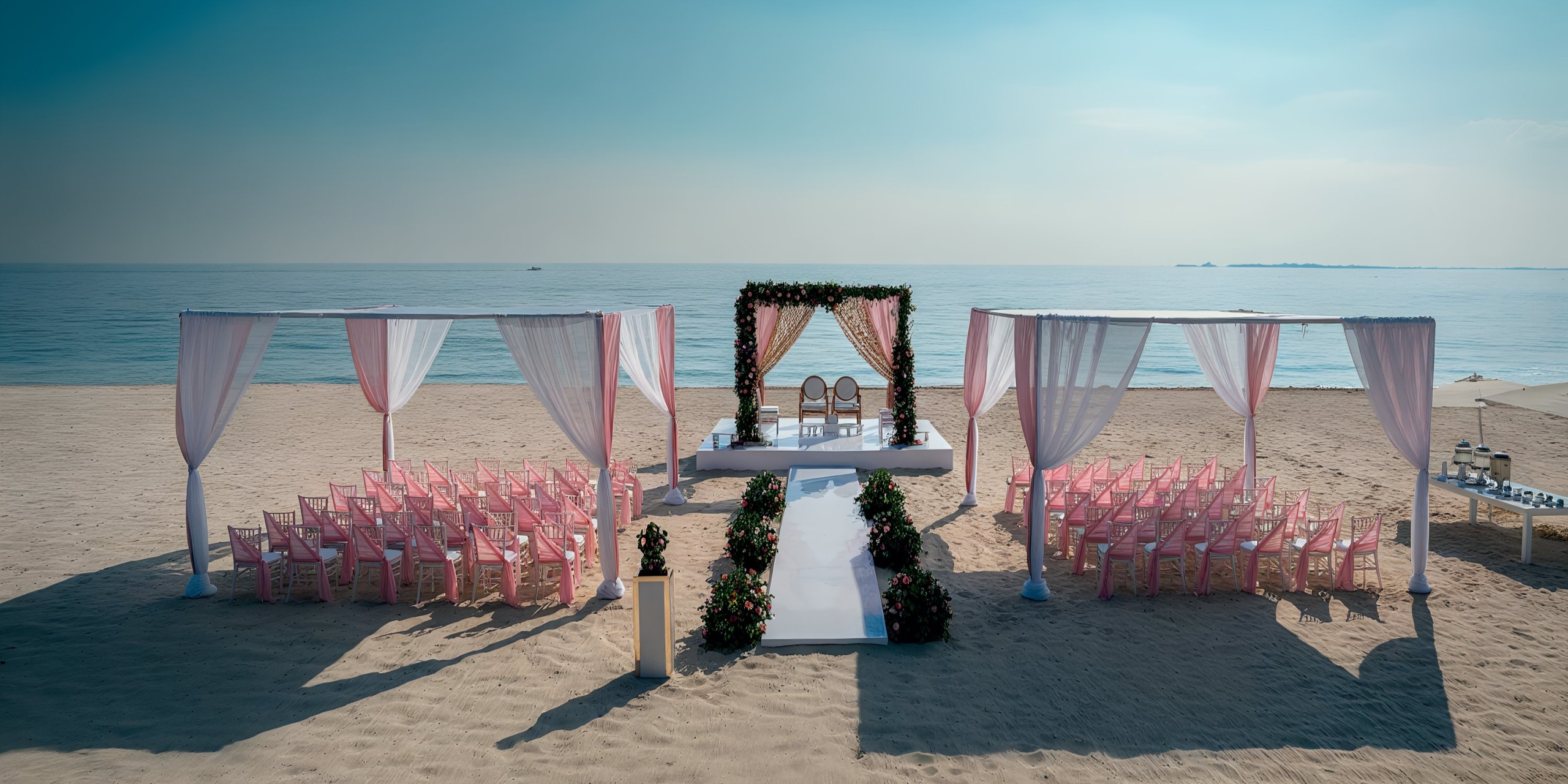 Experience a breathtaking beachfront wedding at the Grand Palladium Costa Mujeres, featuring elegant pink chairs, a pristine white aisle, and a stunning floral arch all set against the backdrop of the ocean.