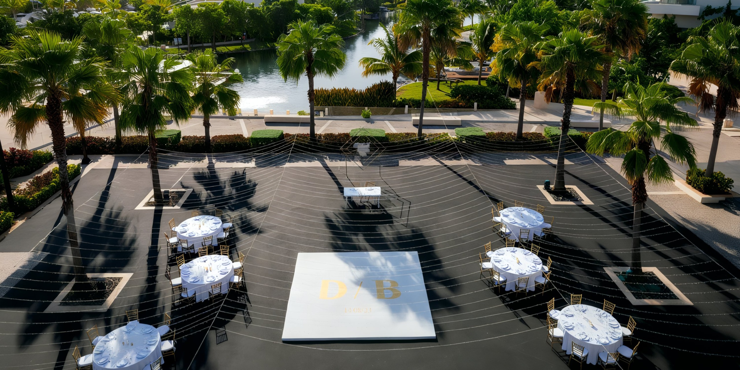 The Grand Palladium Costa Mujeres features an outdoor event space highlighting a central dance floor surrounded by round tables adorned with white tablecloths and chairs, set against a backdrop of palm trees and a scenic waterway.