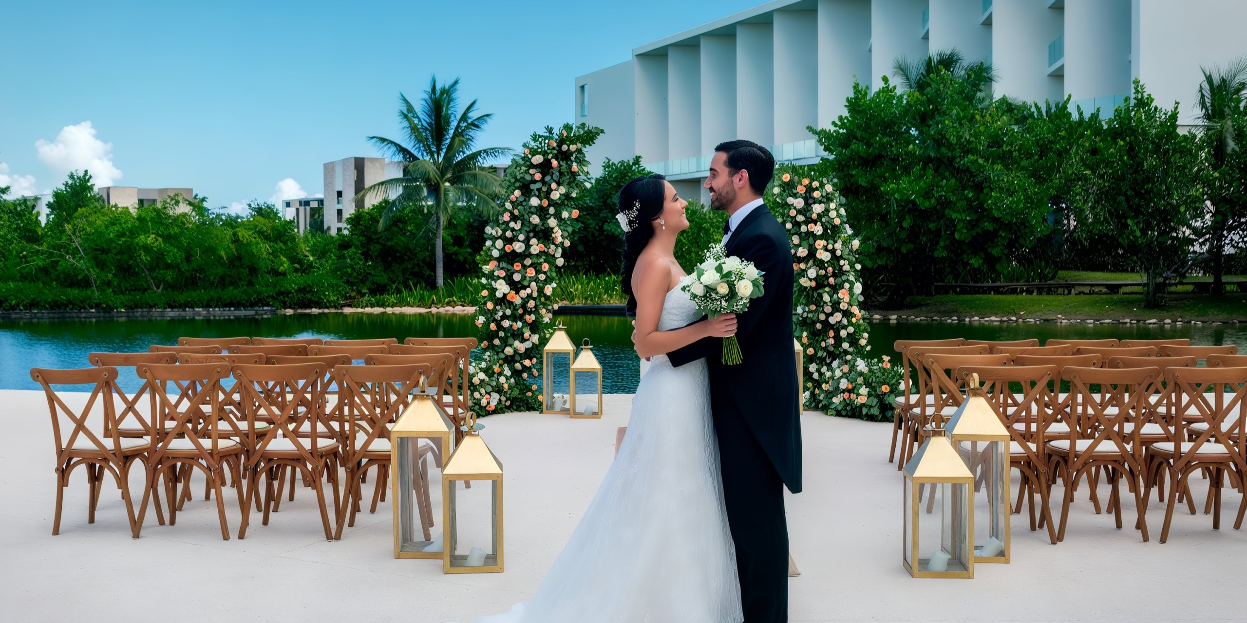 At the Grand Palladium Costa Mujeres, a bride and groom stand facing each other, holding a bouquet amidst an outdoor wedding setting complete with a decorated arch, chairs, and lanterns.