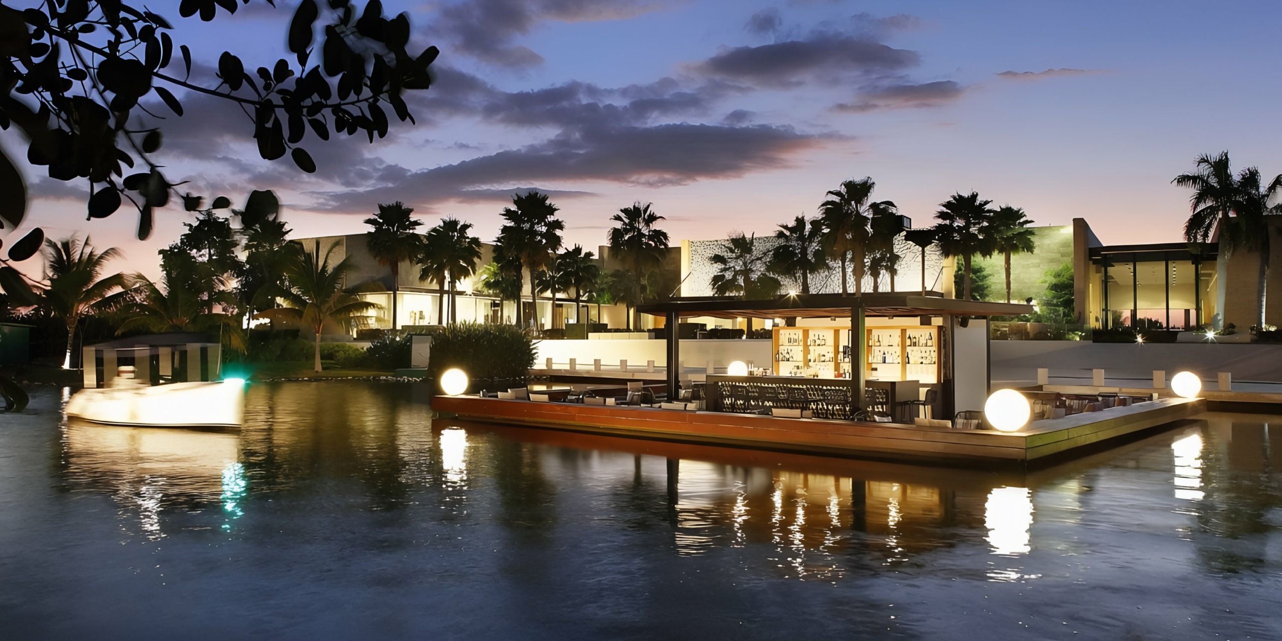 A tranquil evening at Grand Palladium Costa Mujeres with a waterfront dining area and boats under a dusk sky.
